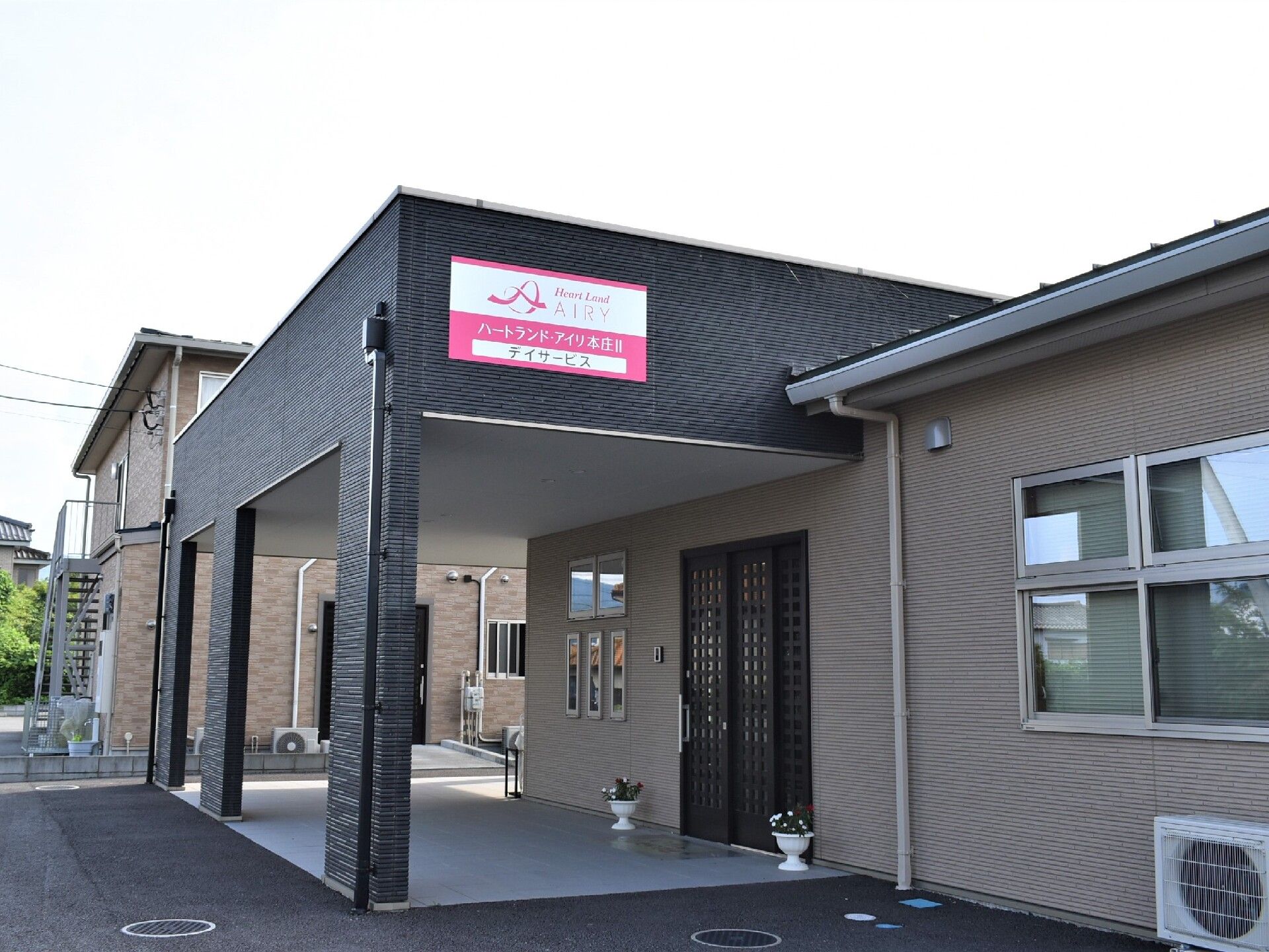 ２階建ての日当たりの良いグループホームである。施設前には広い敷地があり、アスファルトで舗装されている。
