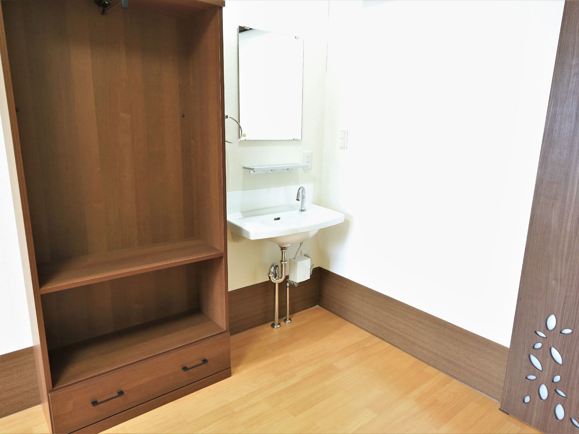 居室にはコンパクトな洗面台が壁に建てつけられている。鏡に棚、タオルハンガー、コンセントの差込口も備わっている。