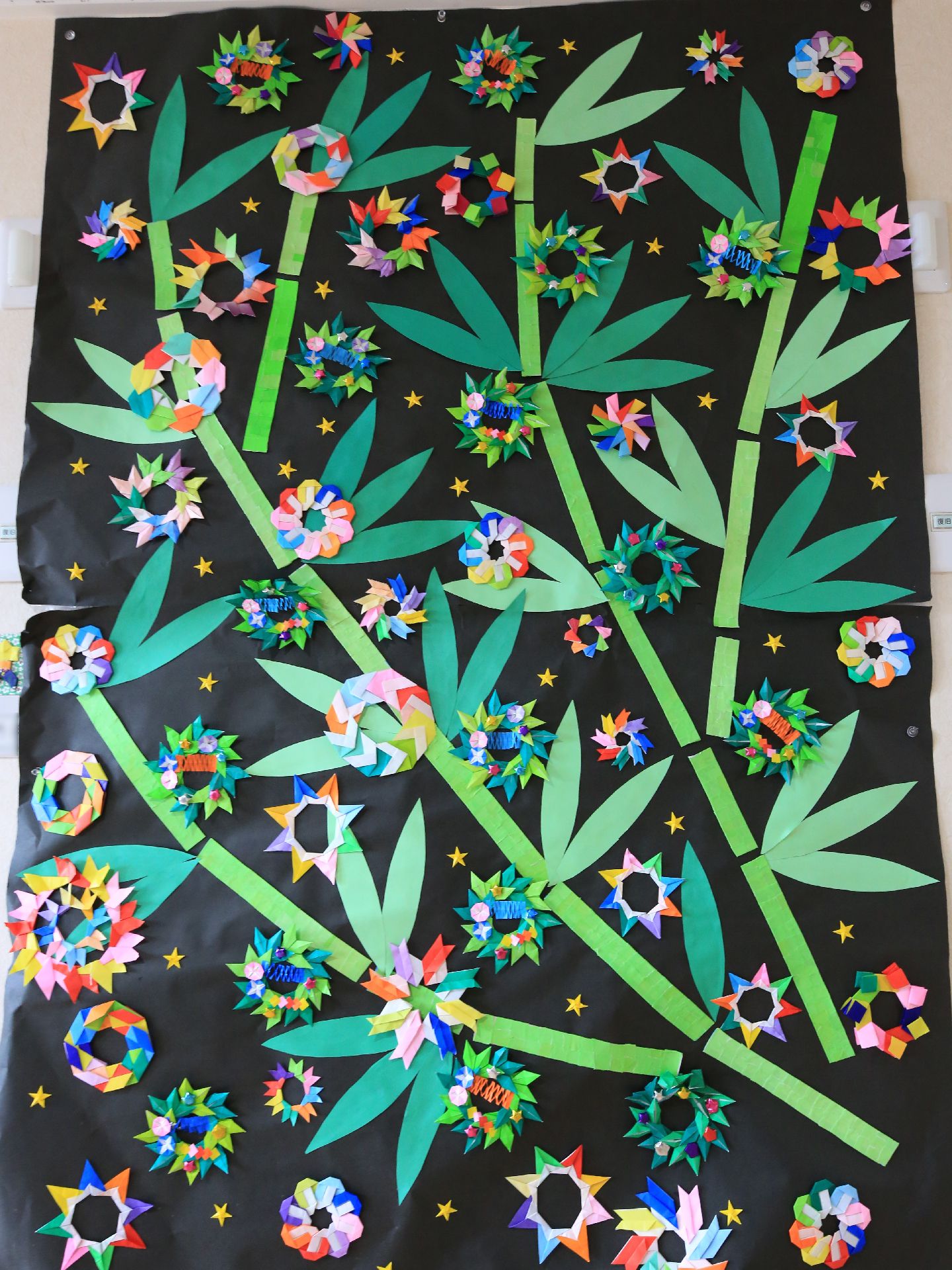 大判の黒い画用紙に、入居者様の手作りの竹と花を模した折り紙が飾られている。手先を動かすことで、身体機能の向上を図るというメリットがある。