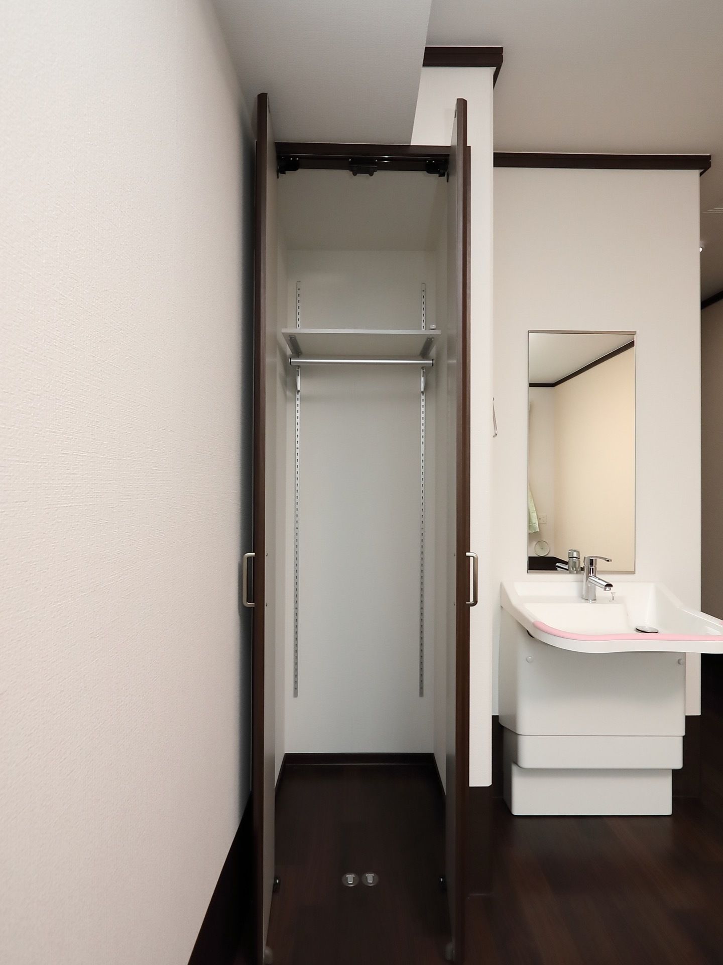 居室の壁には、天井の高さのクローゼットが設置されている。その横には洗面ボウルの広い、使いやすい洗面台が備わっている。