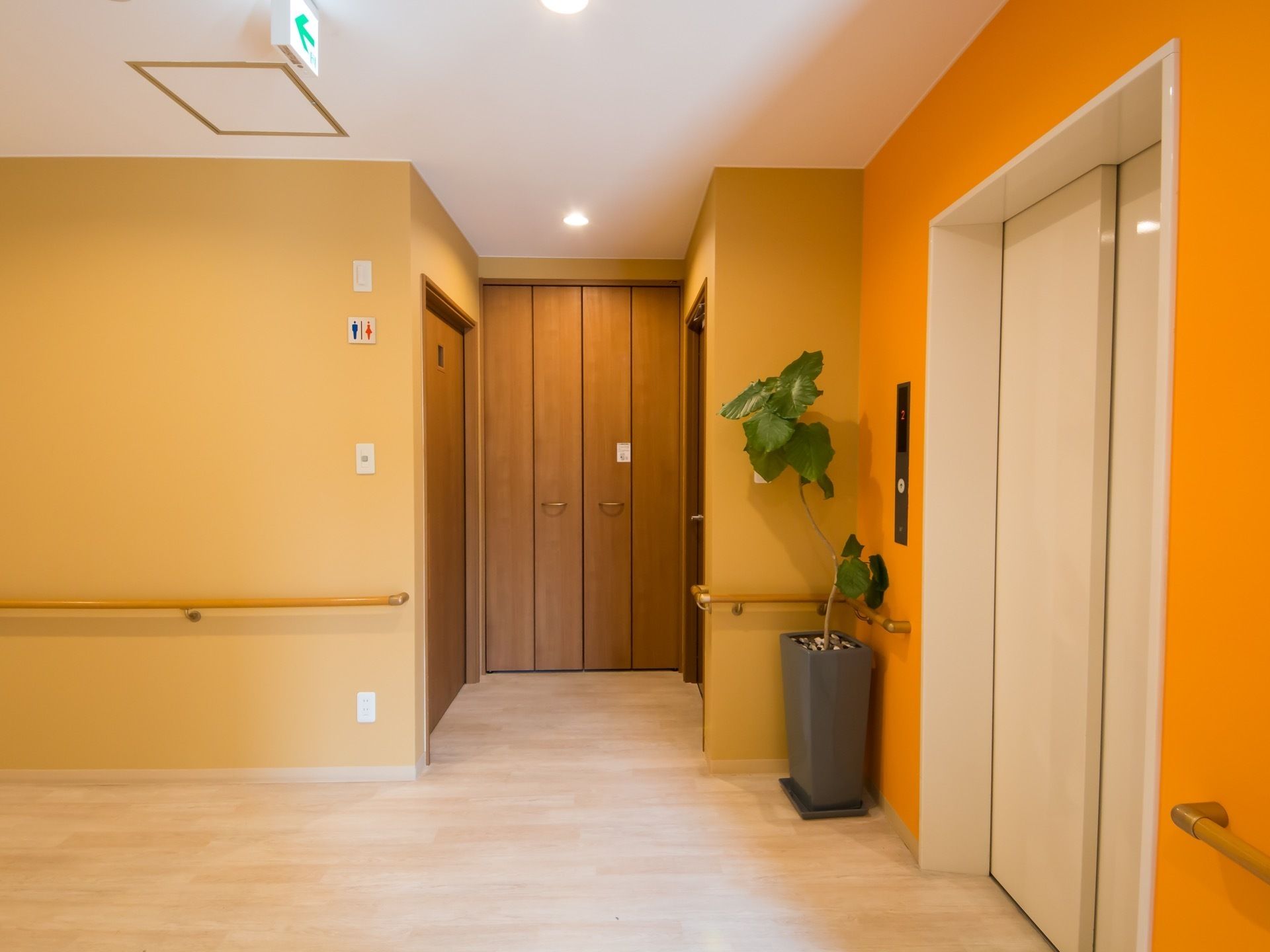 落ち着きのあるモダンな雰囲気のある廊下である。トイレやエレベーター、収納スペース、手すりが完備されている。