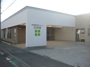 広々とした敷地に建てられているシンプルな平屋の建物。外壁には施設名が掲げられている。入口には屋根が付いている。