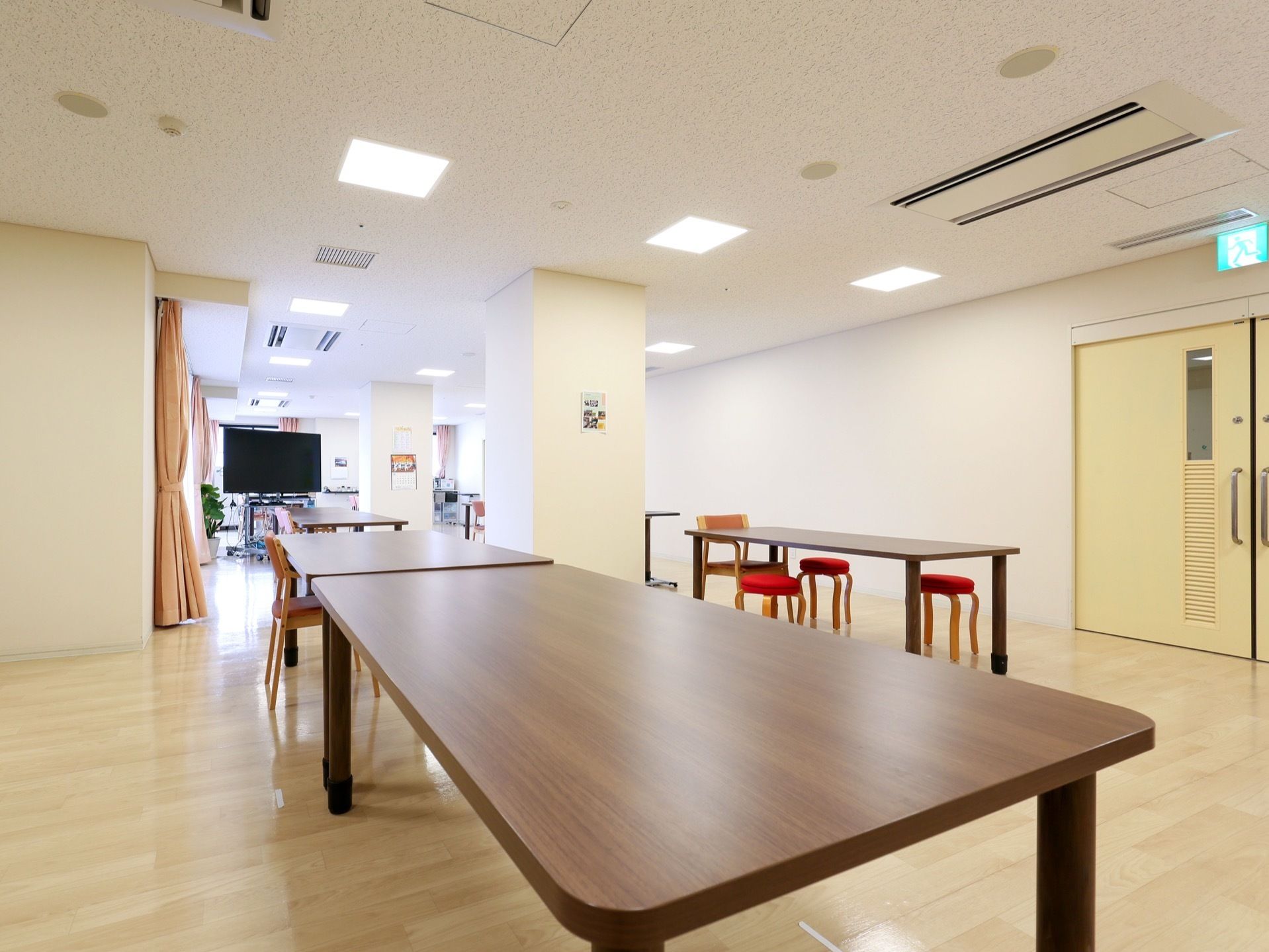 白っぽい床色に施された、共有のスペースである。中央に落ち着いた色合いの、ダイニングテーブルが置かれている。