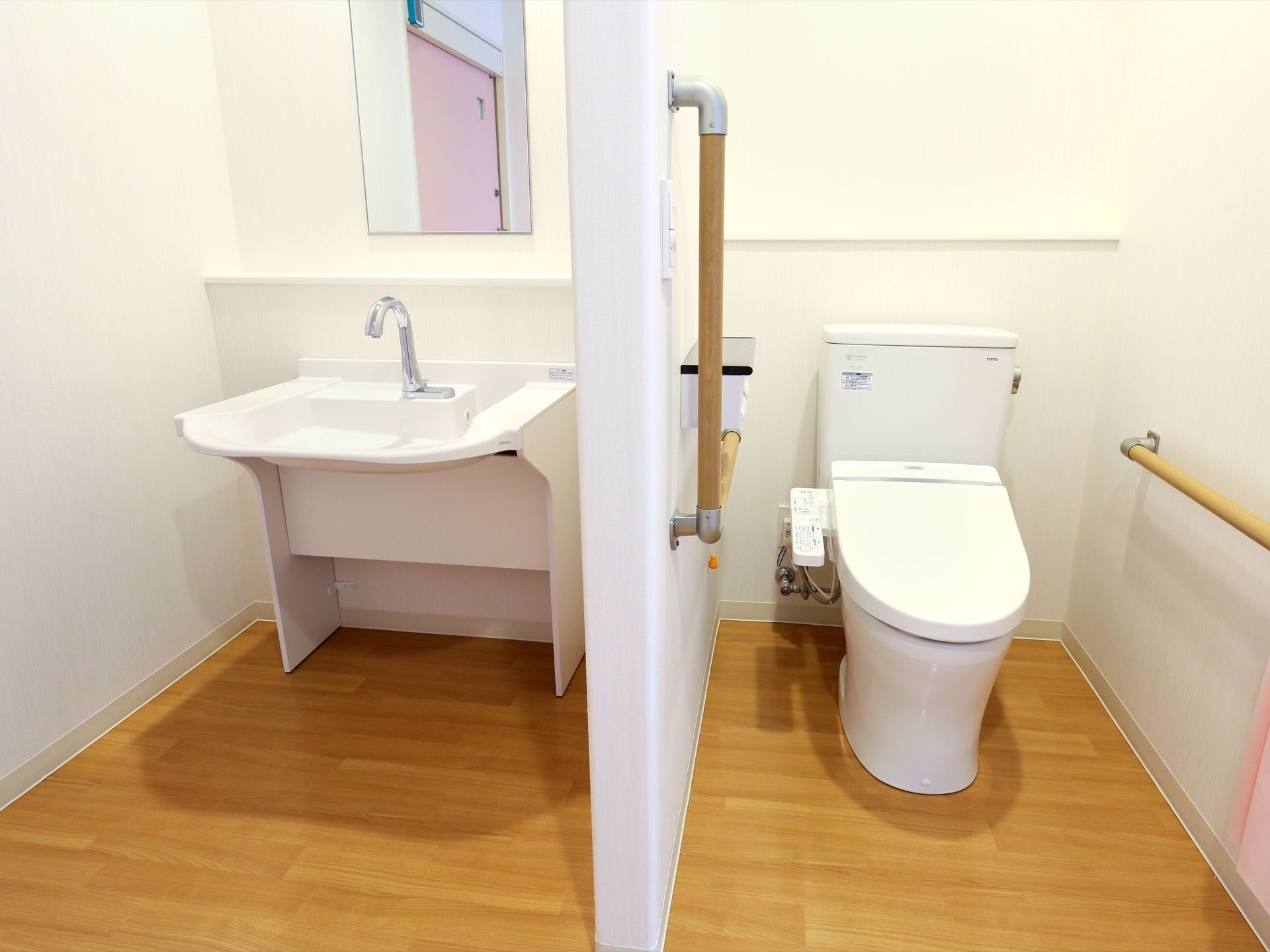 フットレスの洗面台と洋式のトイレがあり、それぞれの間は壁で仕切られている。温水洗浄便座がある。