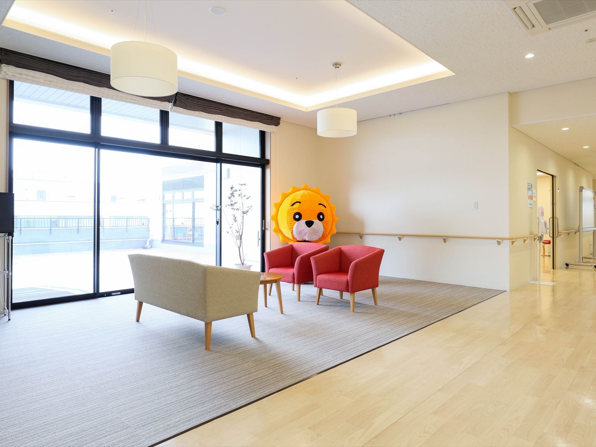 ソファとテーブルが置かれたロビーである。コーナーに存在感あるぬいぐるみが飾られている。つり下げ式の照明もある。