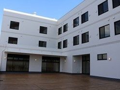 白一色の外観は、スッキリとした印象である。建物前は、広々としたスペースを設け、車椅子をご利用の方でも気持ち良く移動が行える。