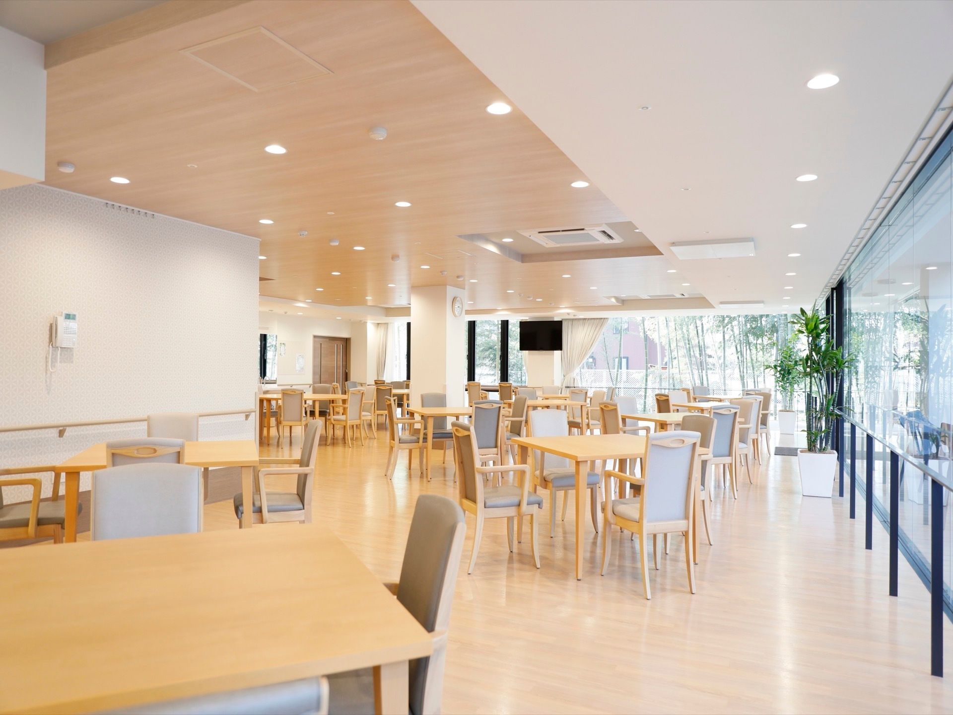 食堂内に置かれたテーブルと椅子は、全て同じ物で統一している。窓の近くにテレビを配置している。天井にはエアコンがある。