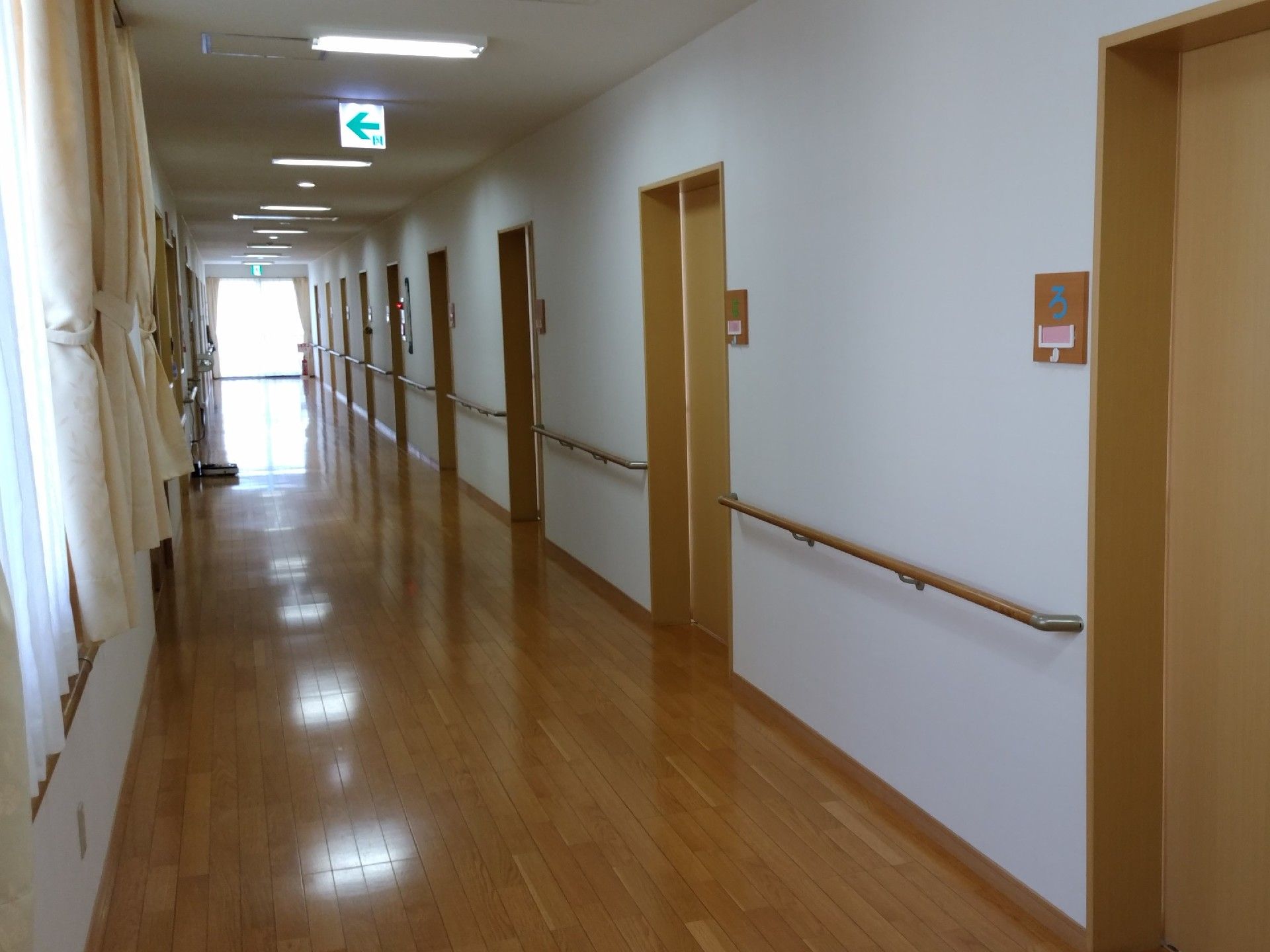 通路の天井には複数の照明が設置されている。バリアフリー設計で快適に移動できる。白い壁に手すりが備え付けられている。