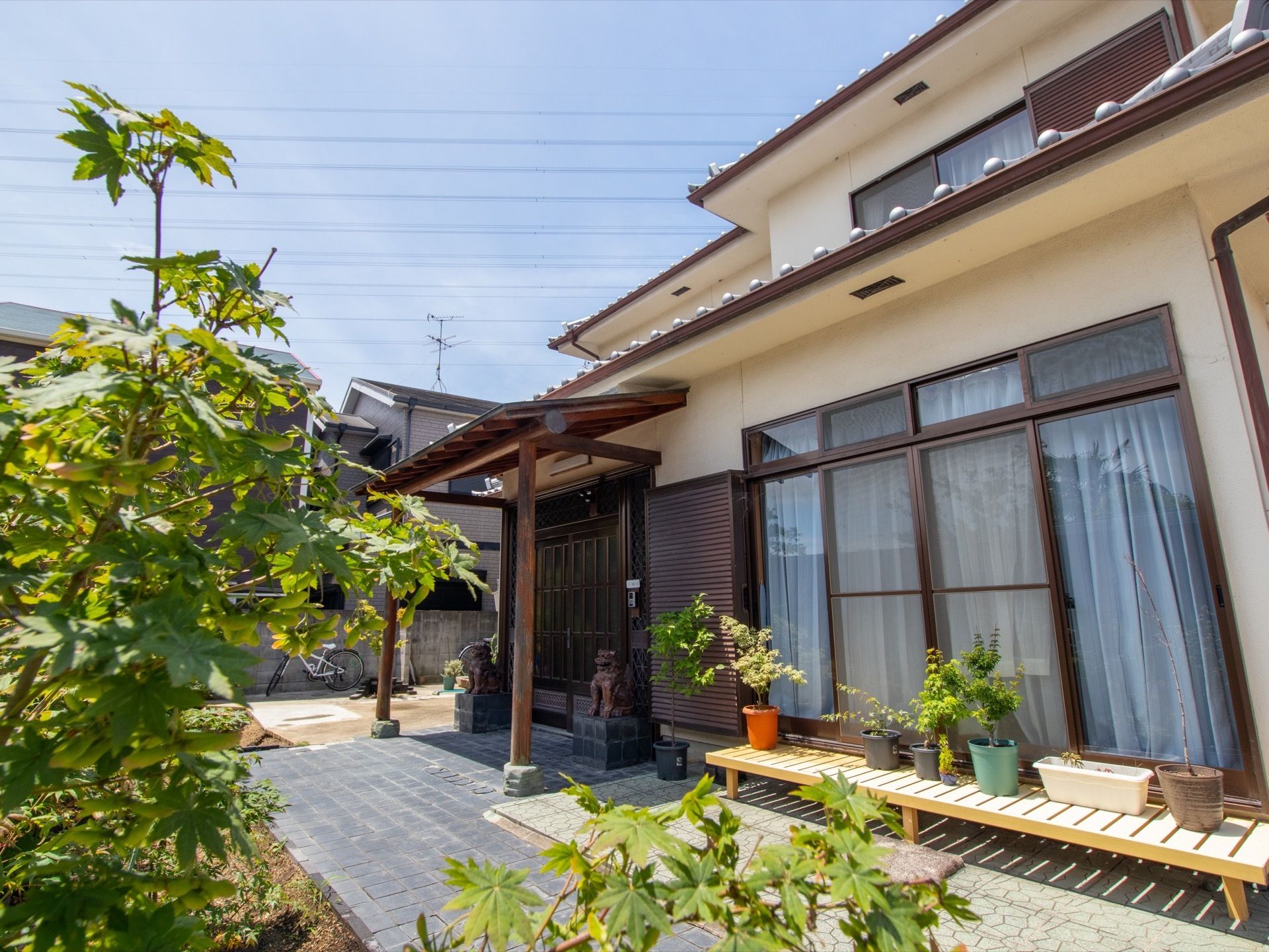 玄関の前には２匹のシーサーが置かれている。玄関扉の隣には多くの入居者様が座れる縁側が設置されている。