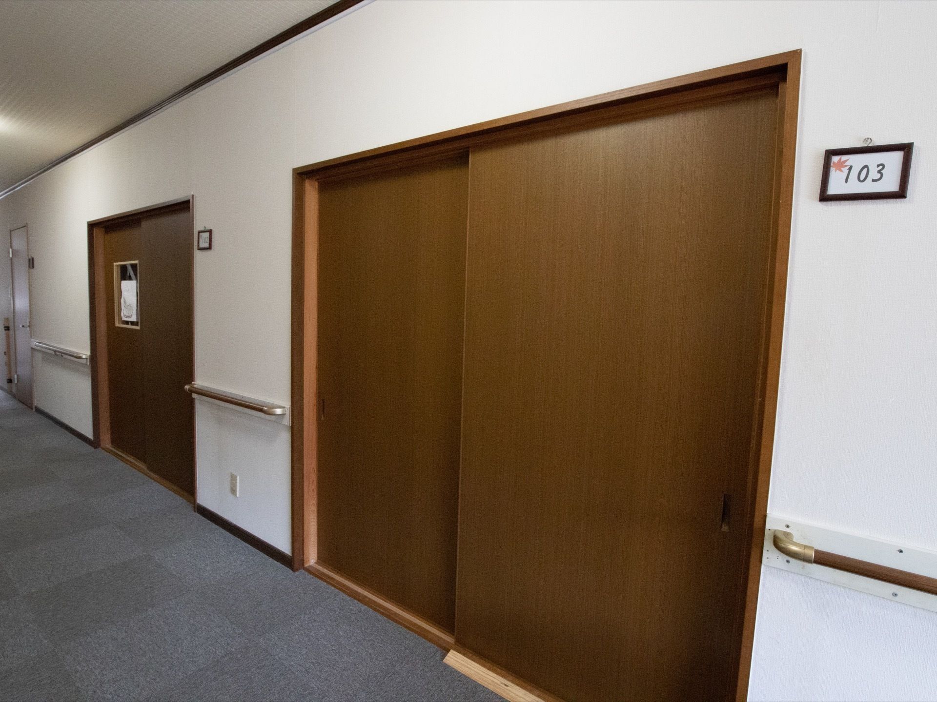 部屋の扉は木製で引き戸式になっている。扉の近くには部屋番号が入ったプレートが付けられている。壁には手すりがある。