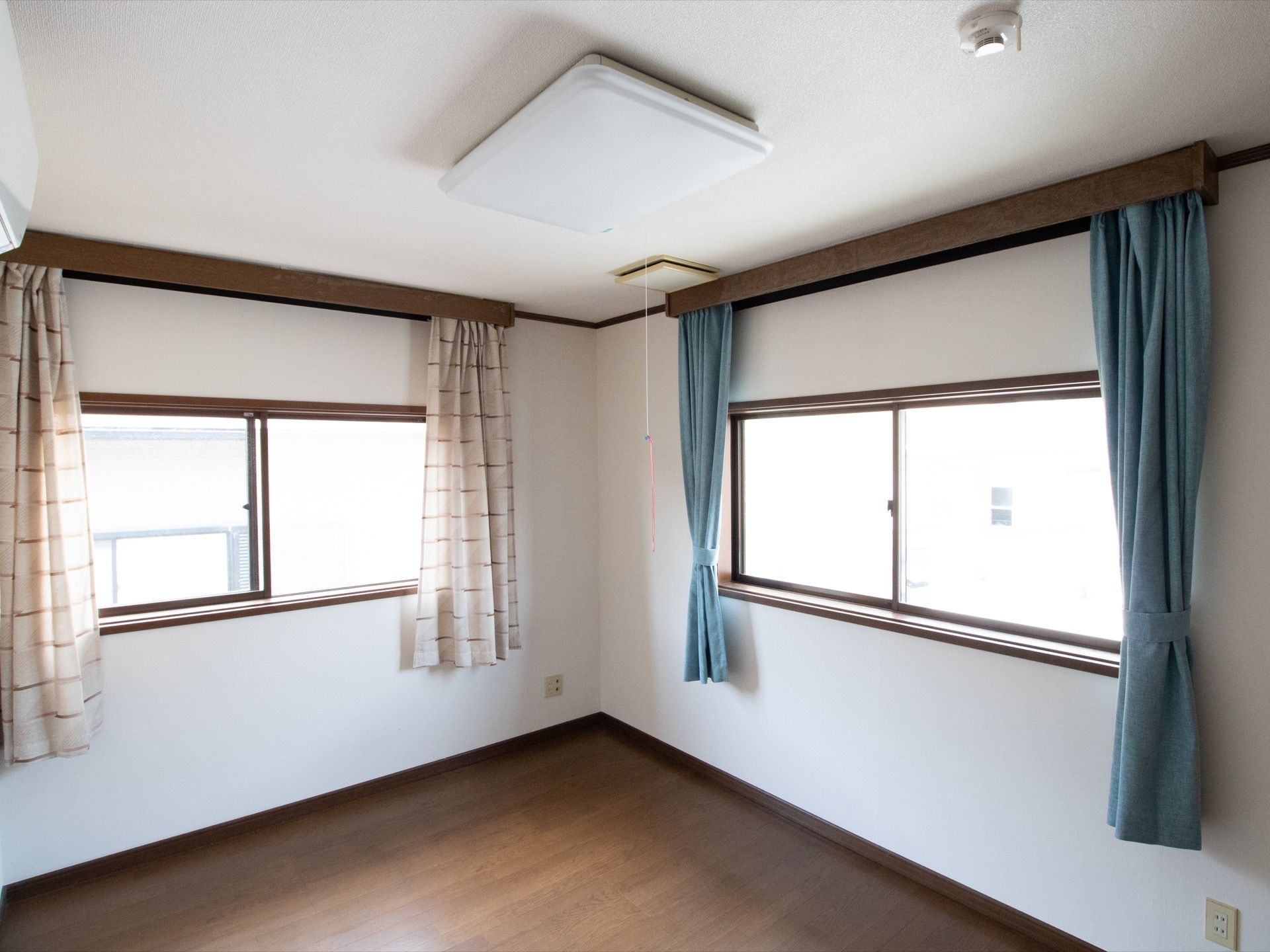 天井の照明から紐が垂れ下がり、背の低い入居者様でも電気がつけやすくなっている。窓の下にはコンセントがある。