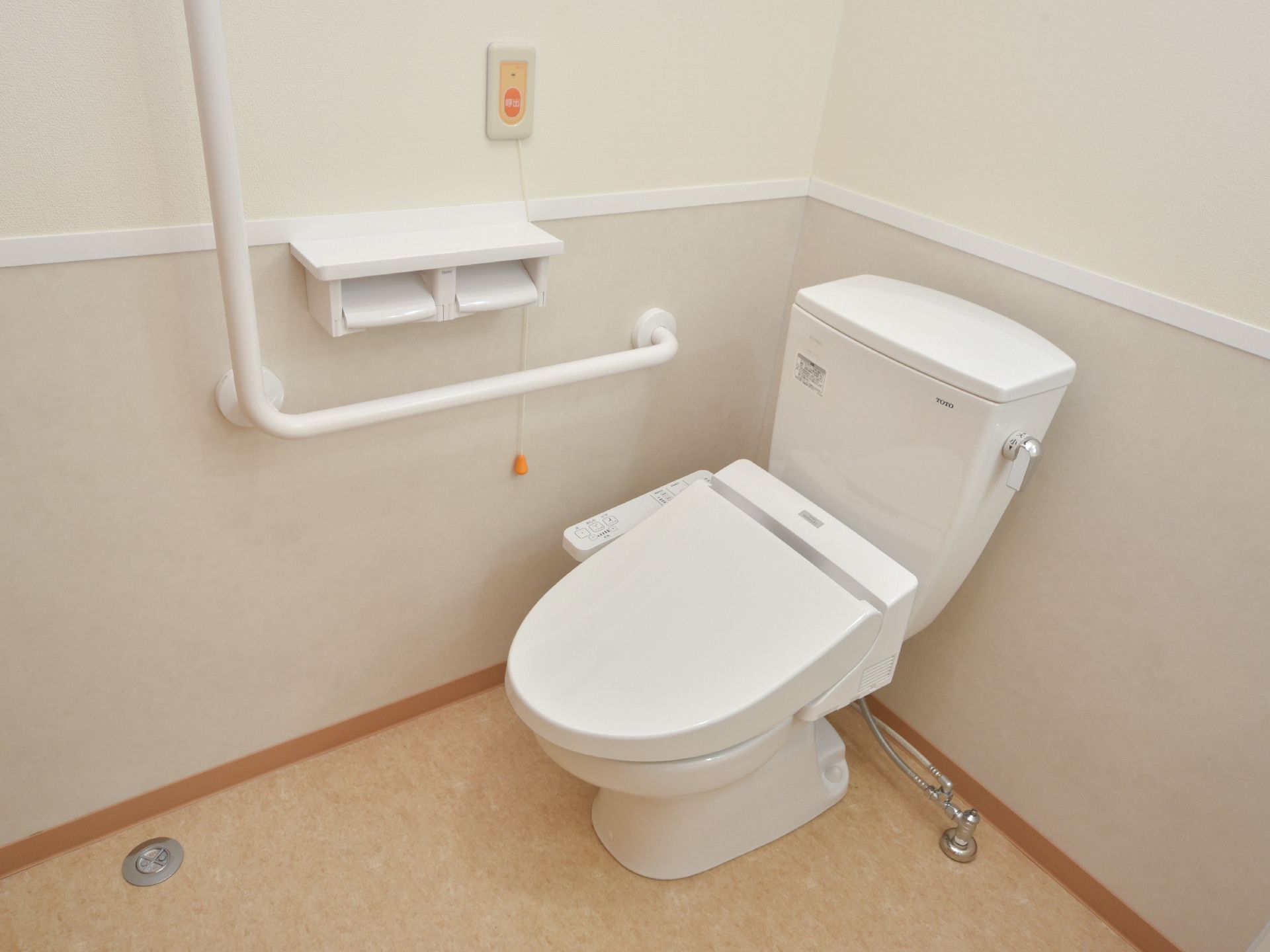 トイレは温水洗浄便座付き洋式トイレである。右手壁にL字の手すりがありペーパーホルダーと緊急通報ボタンがある。