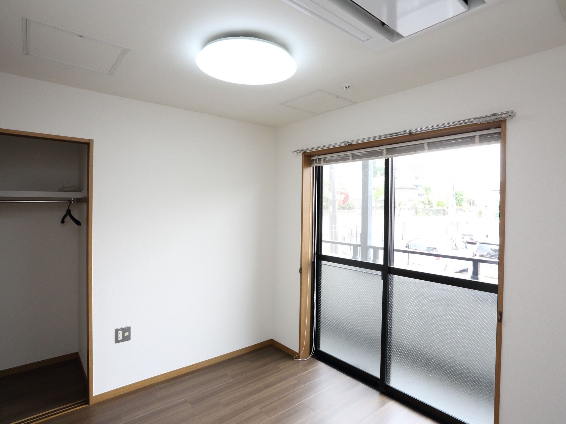 エアコンは天井にある。フロアは暗色のブラウンである。ハンガーがかかる戸棚が設置してあるため、衣類のシワを防いで保管することが可能だ。