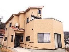 ベージュ色の外壁の落ち着いた雰囲気の建物である。壁には手すりを設置しており、体を支えながら移動することができる。
