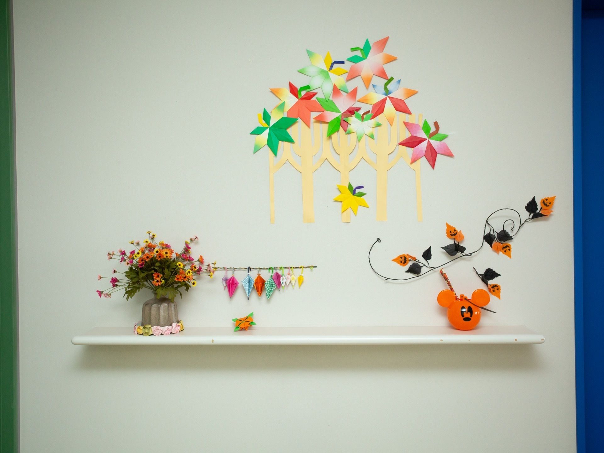 壁に小さな棚板が付いており、その上や周辺の壁に折り紙などで作った飾りがされている。ハロウィンの飾りもある。