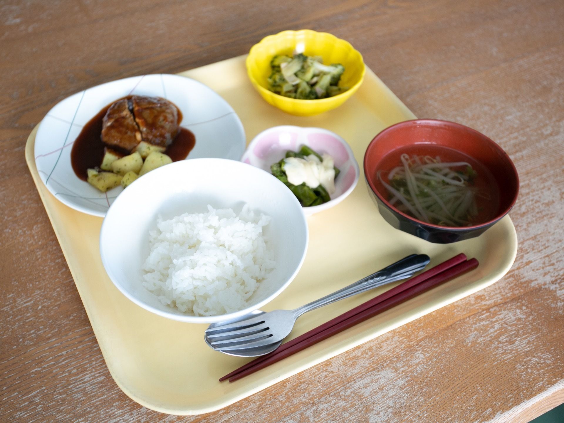 トレーの上にご飯と味噌汁、おかずが３品載っている。野菜が多く、それぞれ食べやすい大きさに揃えられている。