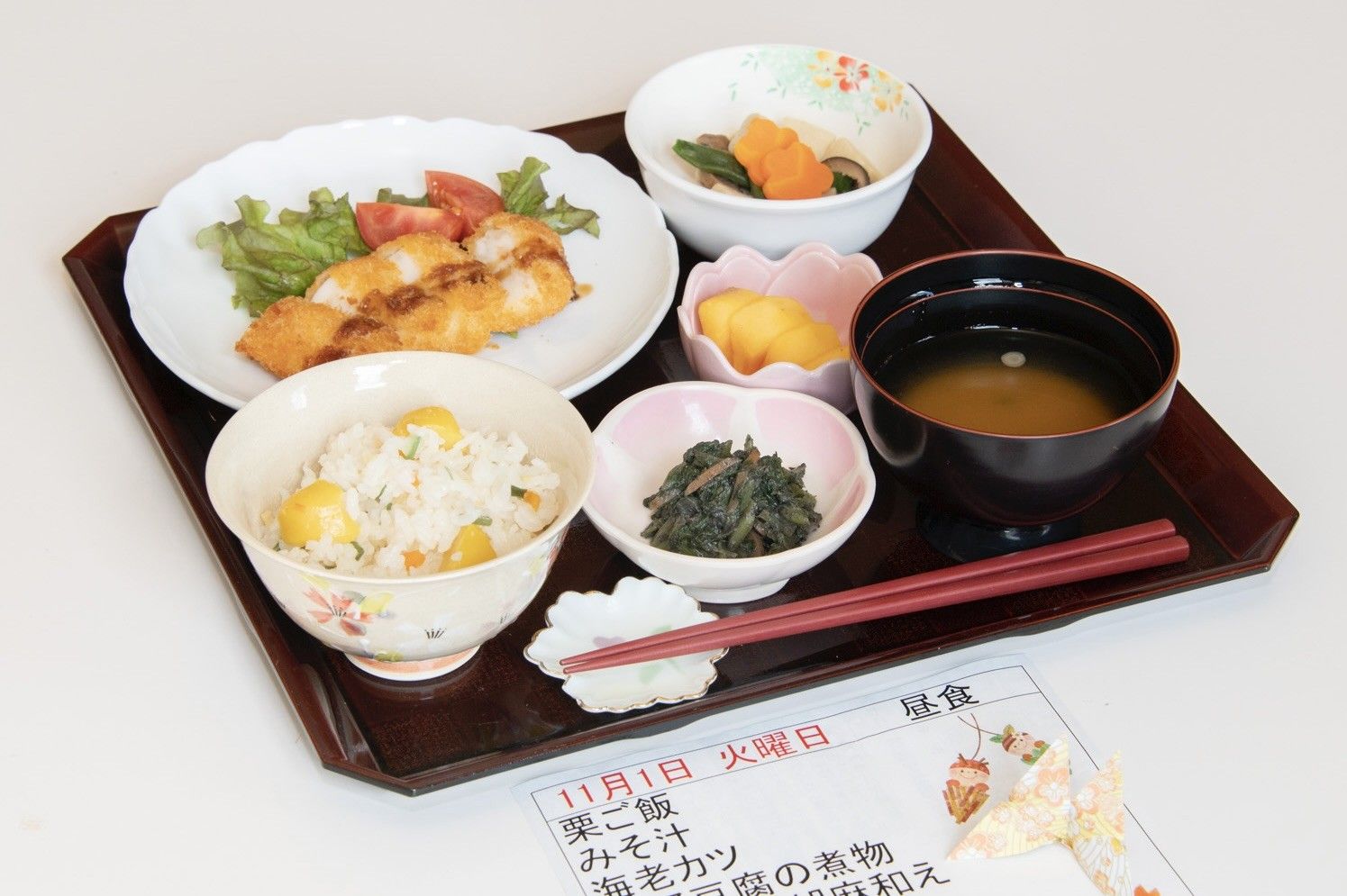 炊き込みご飯や焼き鮭、野菜が豊富な副菜の並んでいる食事