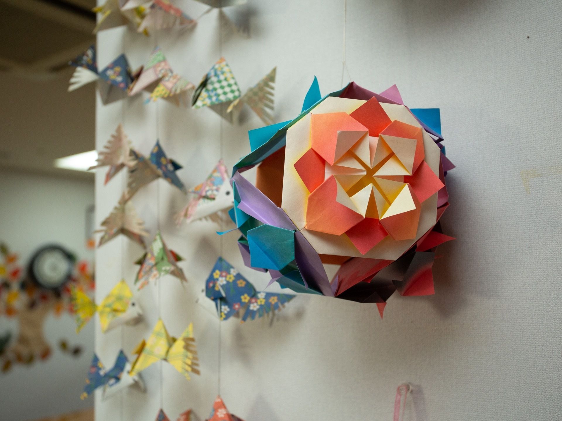 折り紙を折ったものを組み合わせて作った球が紐で吊るされている。たくさんの折り紙の金魚も飾られている。