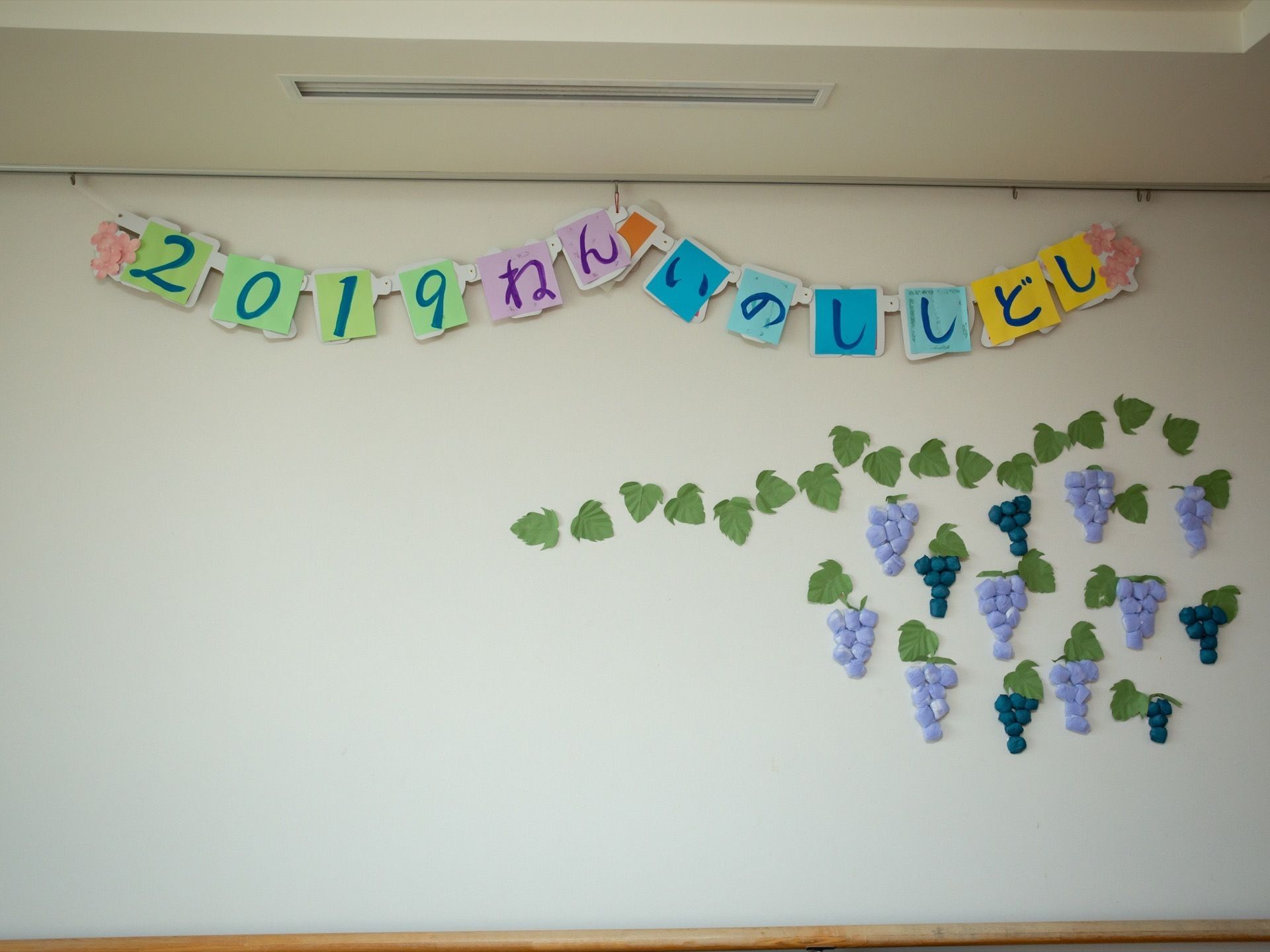 白色の壁に飾られた制作物である。2019ねんいのししどしの文字が12枚の画用紙にそれぞれ１文字ずつ書かれている。