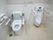 白を基調としたトイレスペースである。便座には背もたれとひじ掛けを備えている。横に男性用便器を設置している。