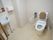 洗面台を備えたゆったりとしたトイレスペースである。鏡の横側には、ハンドペーパーを設置している。便座の傍に手すりを取り付けている。