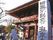 赤い外観の拝殿がある。拝殿の右側には神社の名称が書かれており、左側には狛犬が1体置かれているのが見える。