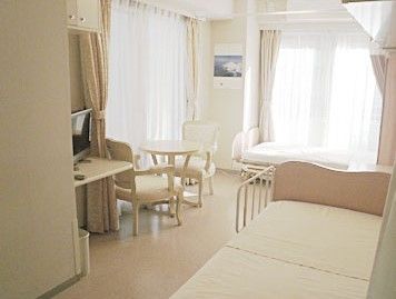 居室にはそれぞれな離れた場所に柵付きのベッドが2台設置されている。丸いテーブルと椅子が置かれた近くにはテレビが用意されている。