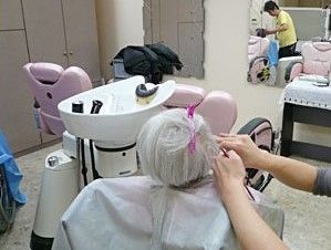 入居者様の伸びた髪を、丁寧に軽く切っているスタッフ