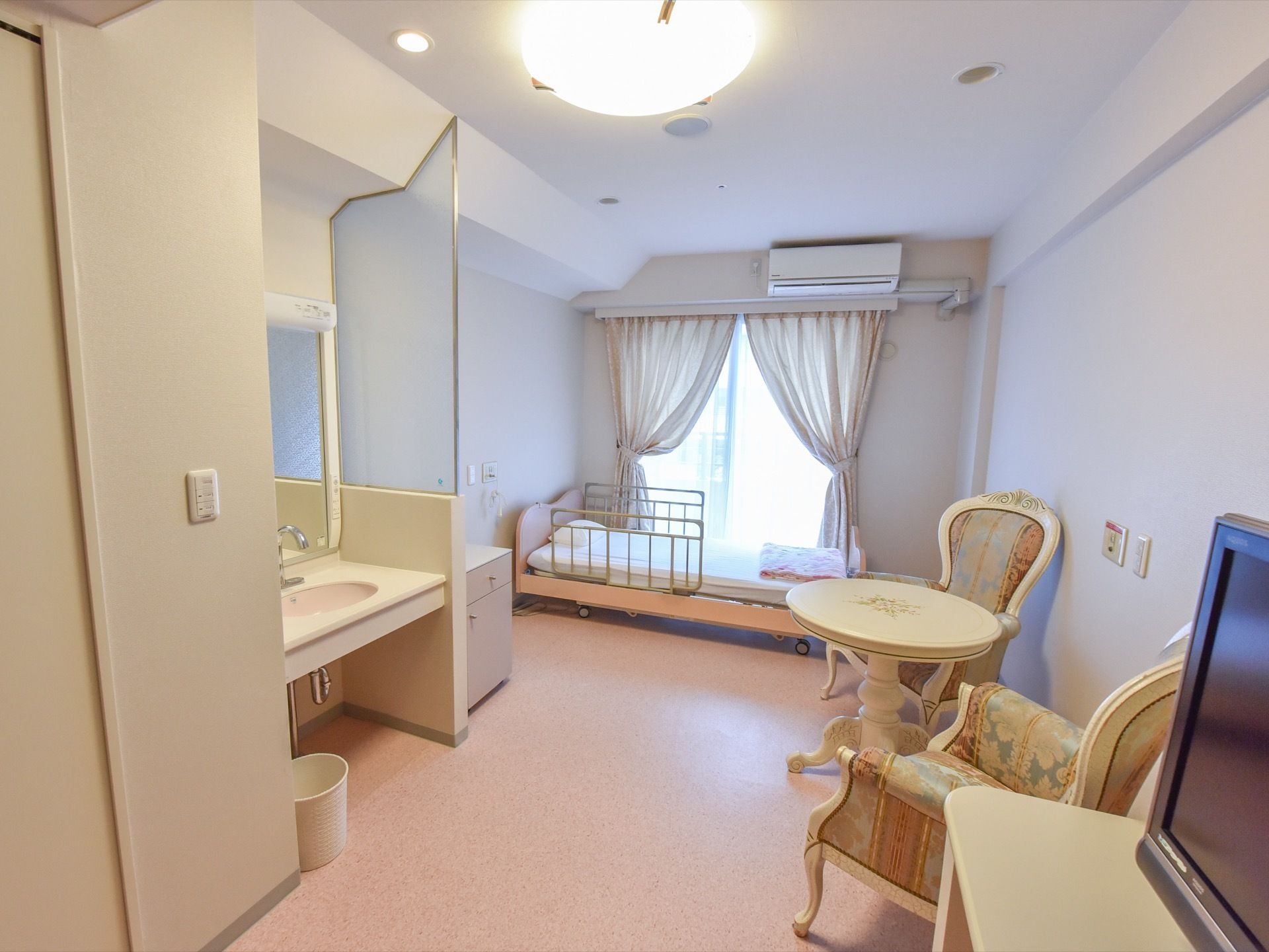 部屋には、淡いピンクのベッドや洋風の柄がついたテーブルセットがある。洗面台には、曇りガラスの仕切りがついている。