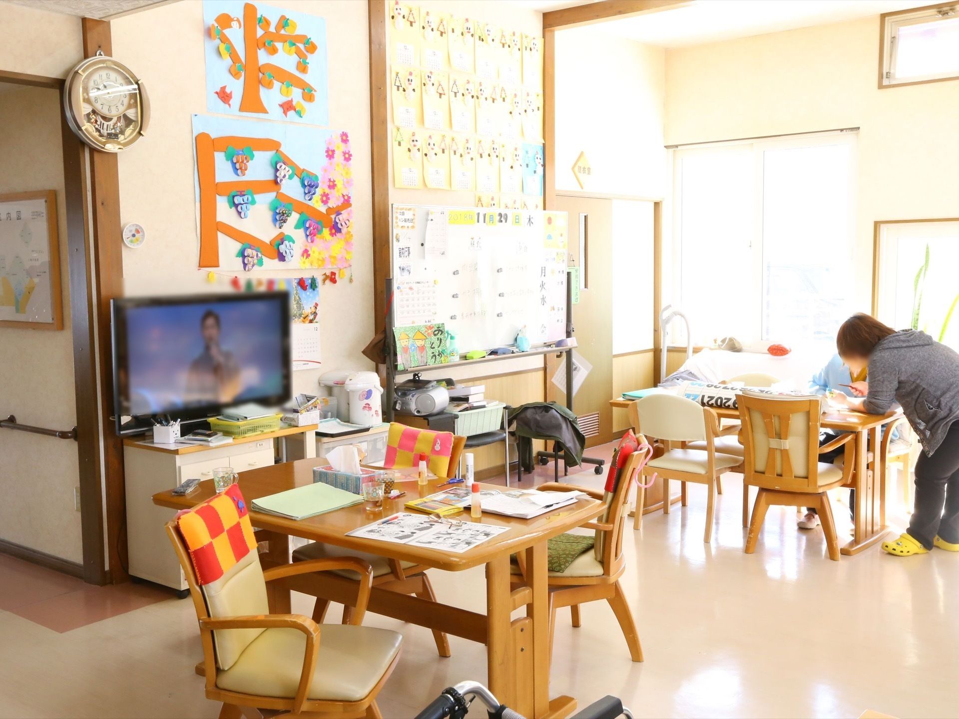 四角いテーブルが置かれ、その周囲に回転式の椅子が置かれている。テーブルの上には糊などの工作道具が広げられている。