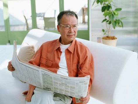 新聞を読む高齢者の居室