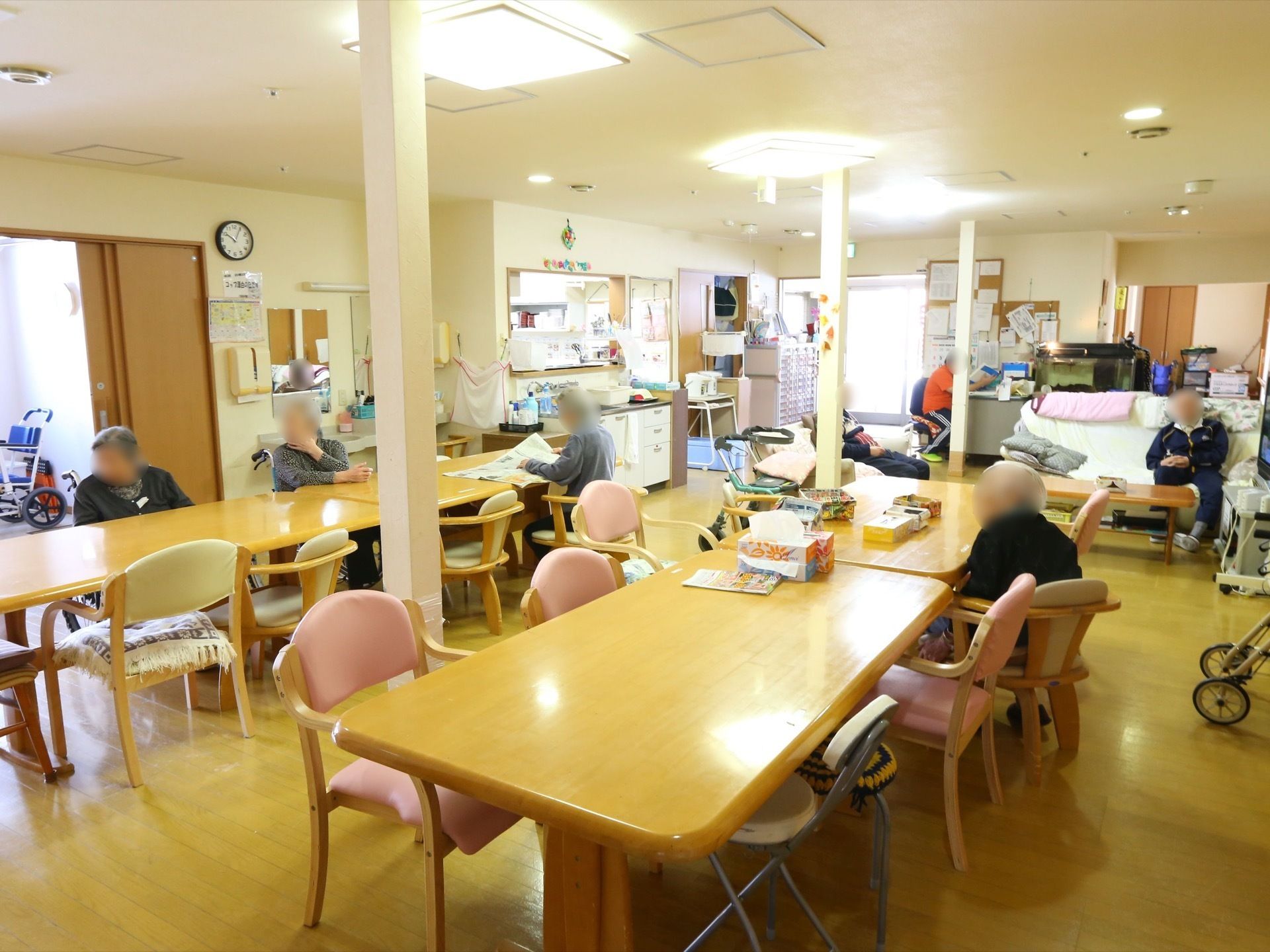 大きなテーブルと椅子が二列並べられている食堂がある。中央には柱が立っている。奥には洗面所とキッチンがある。
