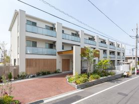 ３階建てのマンションのような建物。２階以上には、ベランダが設置されている。施設内に駐車スペースを設けている。