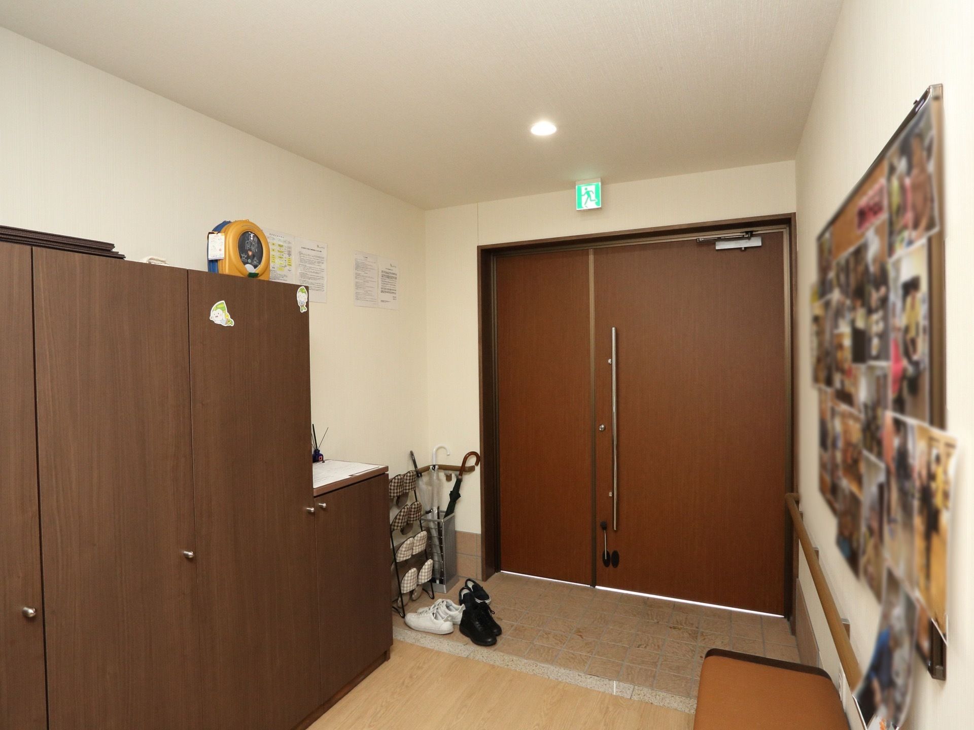 玄関のドアは幅の広い開き戸である。床はバリアフリーである。入って右側に傘立てとスリッパラックが置いてある。