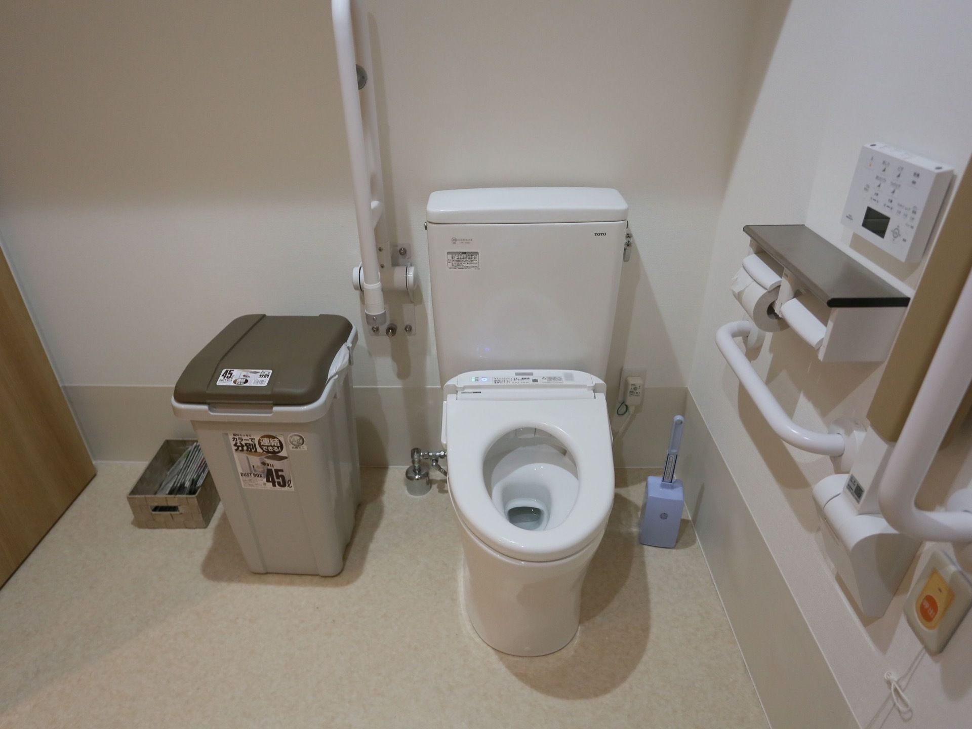 ゆったりとしたスペースのトイレである。便座の横に可動式の手すりを備え、横に汚物などを入れるごみ箱を置いている。
