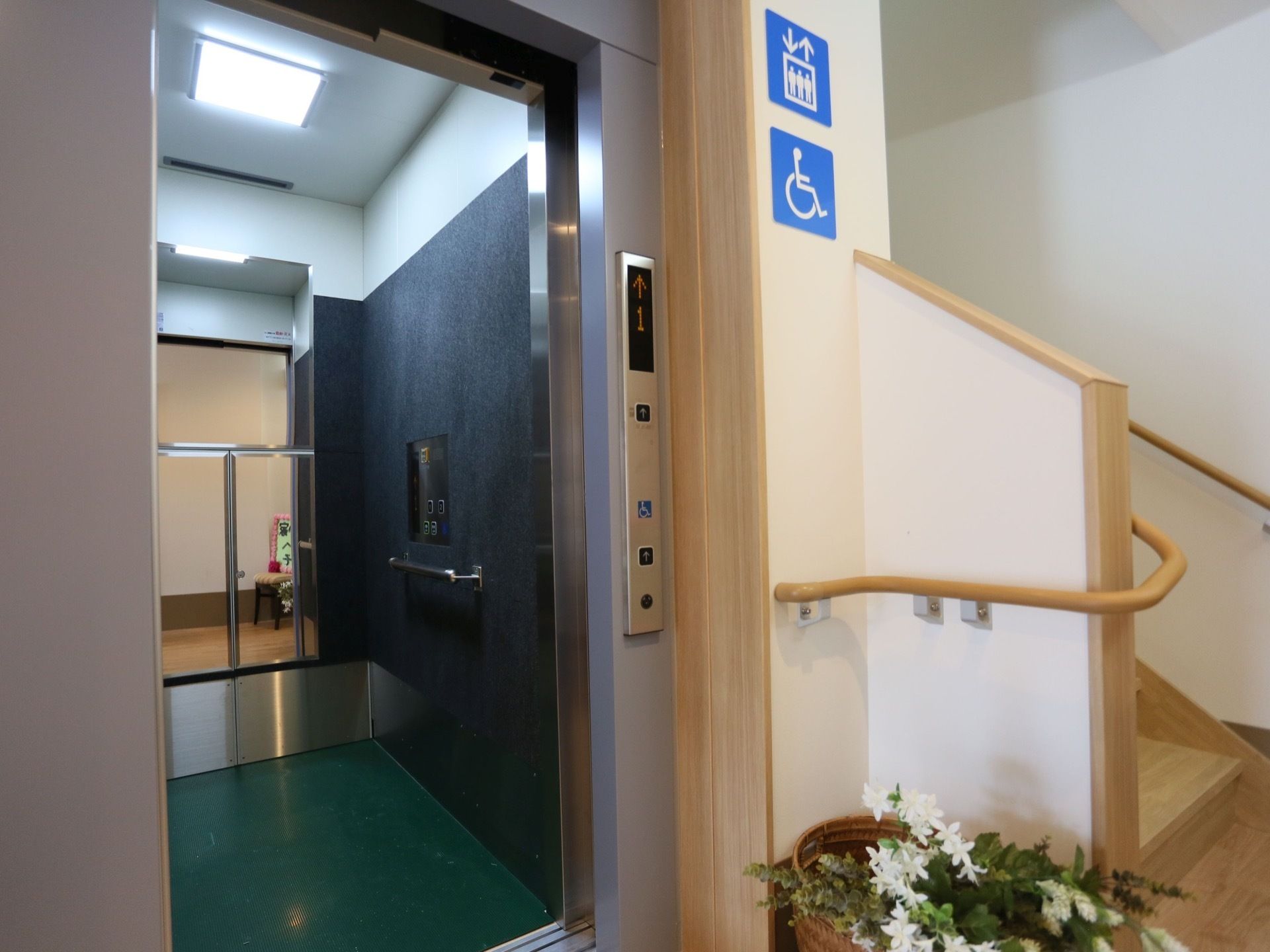 階段の横にエレベーターを設置している。内部は、正面に鏡があり、壁際に手すりを備えている。天井に正方形の照明を取付けている。