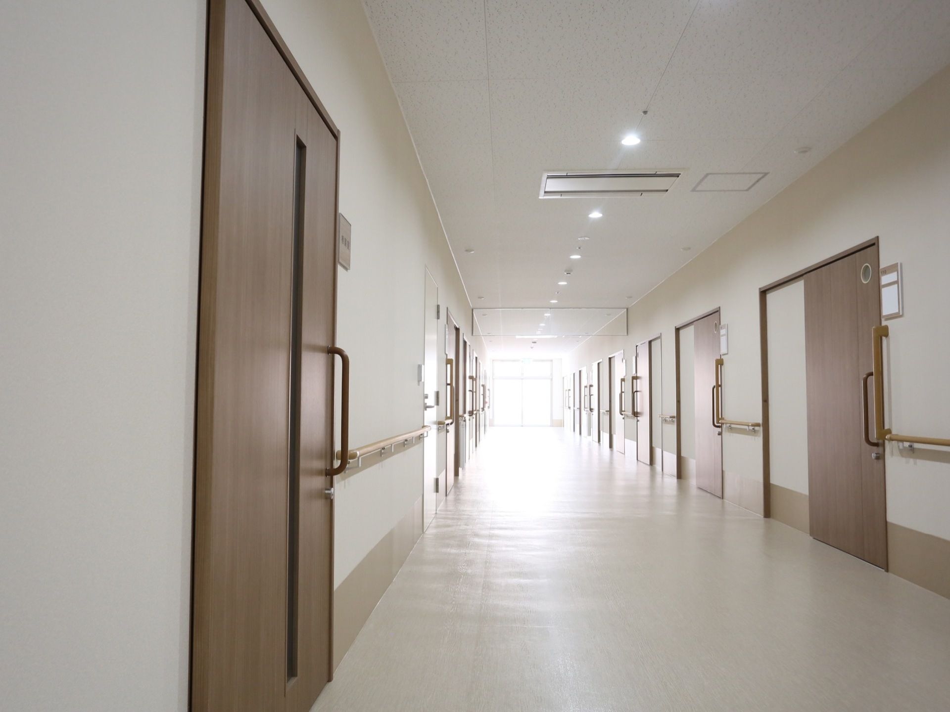 通路の奥には窓があり、明るい光がサンサンと差し込んでいる。ベージュ色の手すりが、両側の壁に取りつけられている。