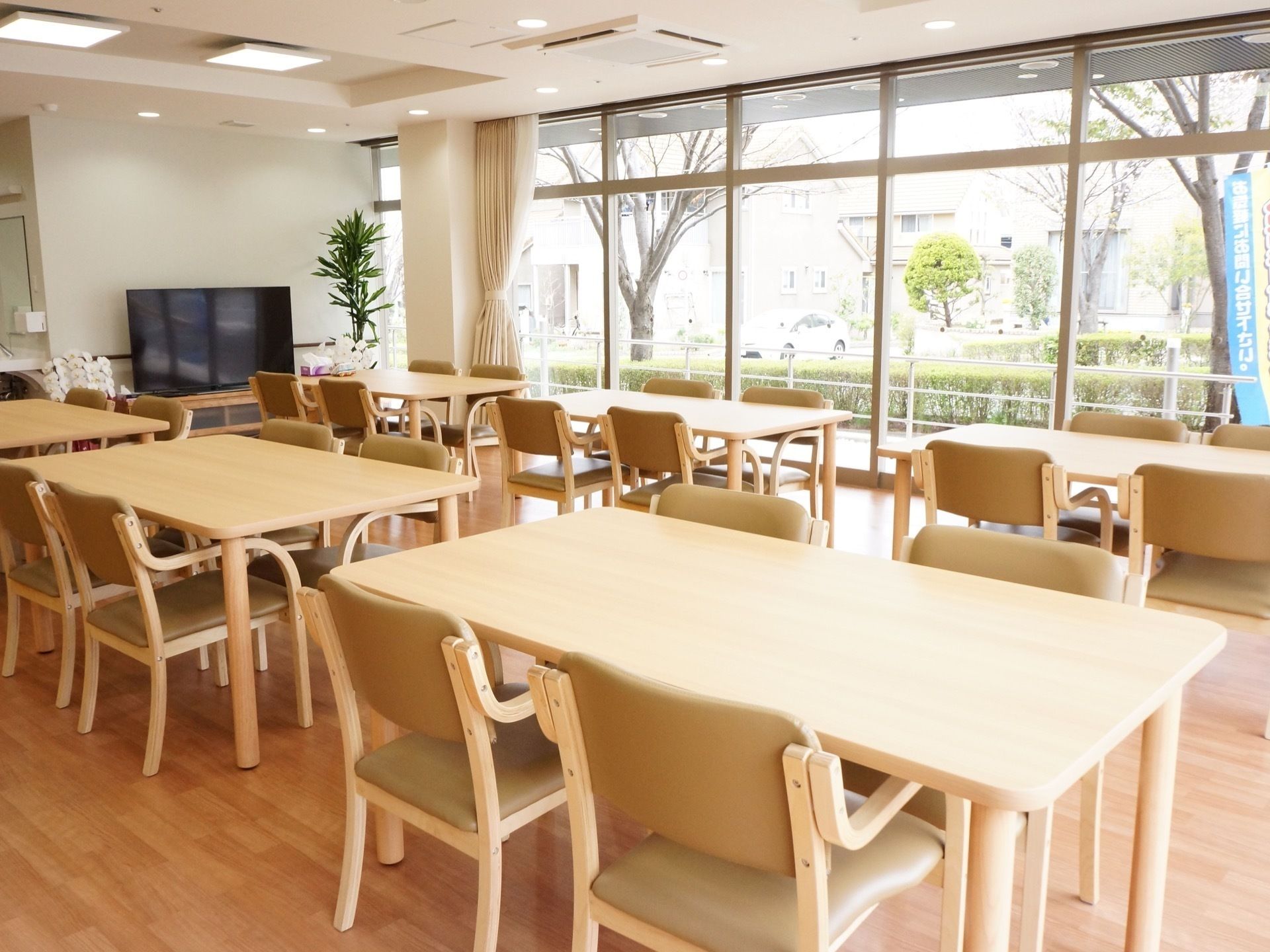 4人掛けのテーブルが並べられた、日当たりのいい食堂