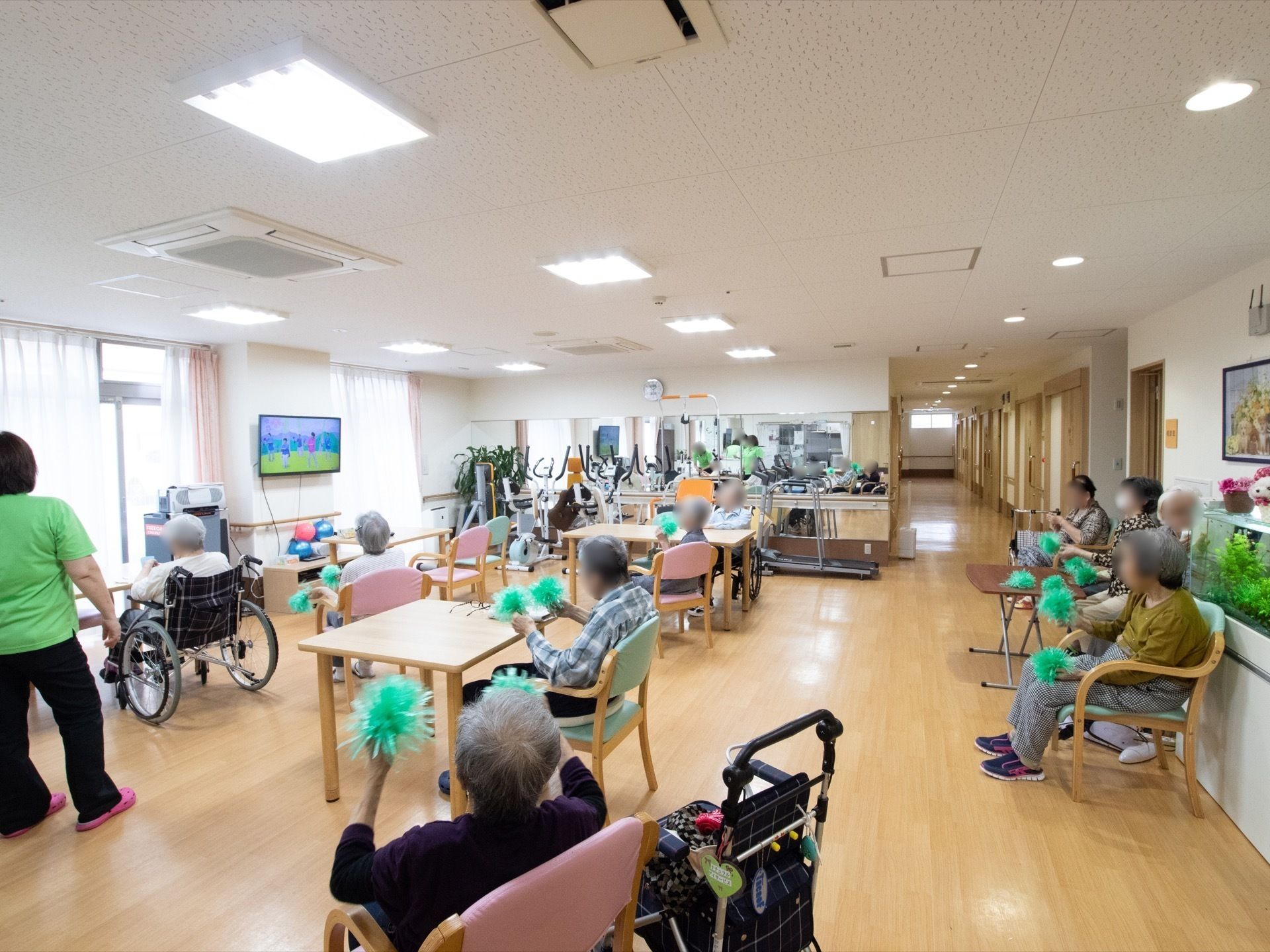 ポンポンを持って、テレビの動きに合わせて運動している入居者様