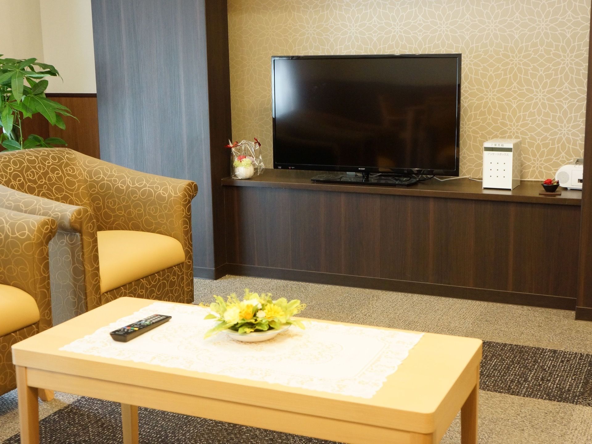造り付けの棚にテレビが置かれている。近くには、ローテーブルとソファーが設置されている。テーブルの上には花が飾られている。