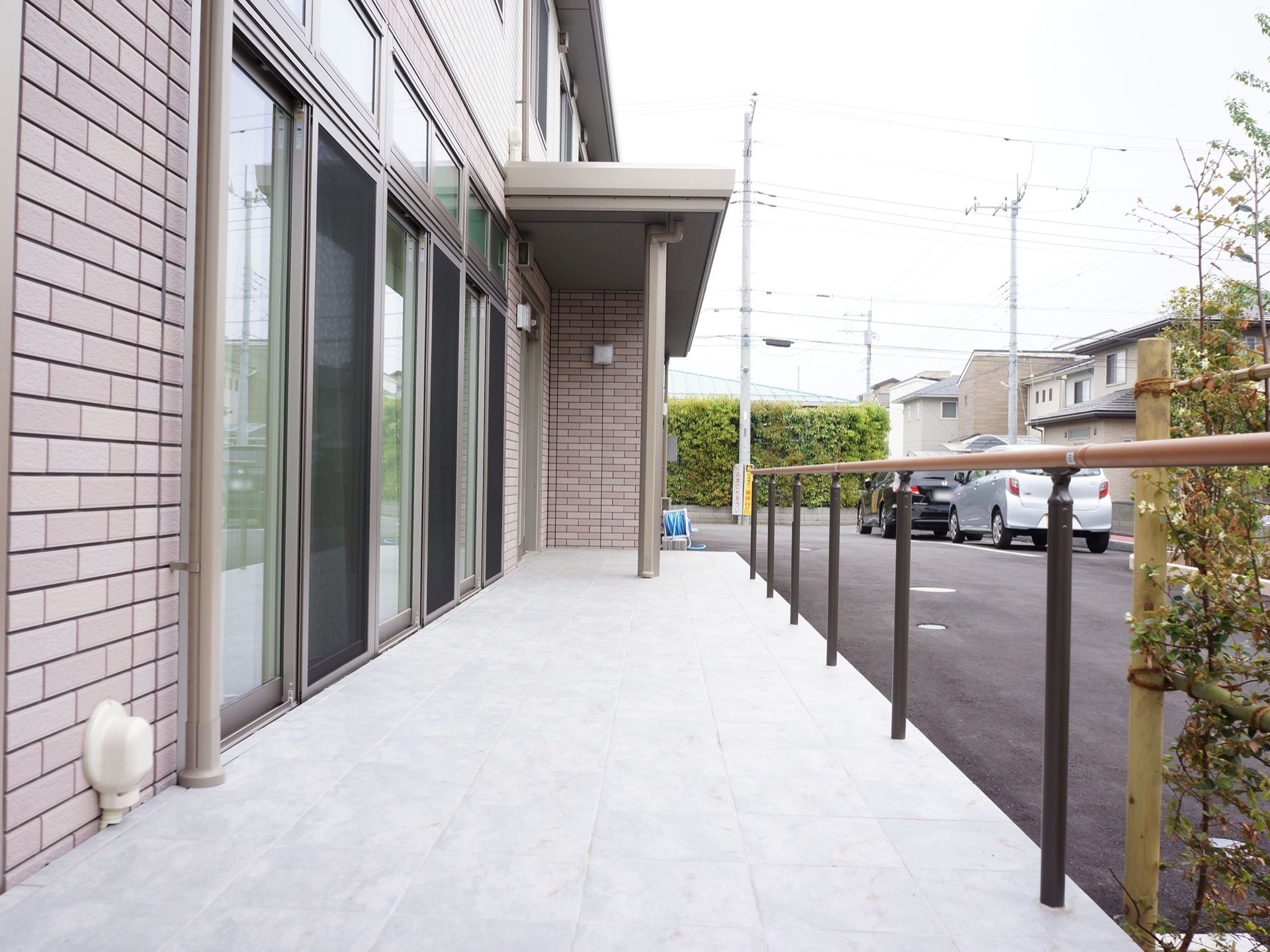施設外から玄関前へは傾斜の緩いスロープが用意されている。手すりが設置され、手すりに沿って植栽が植えられている。