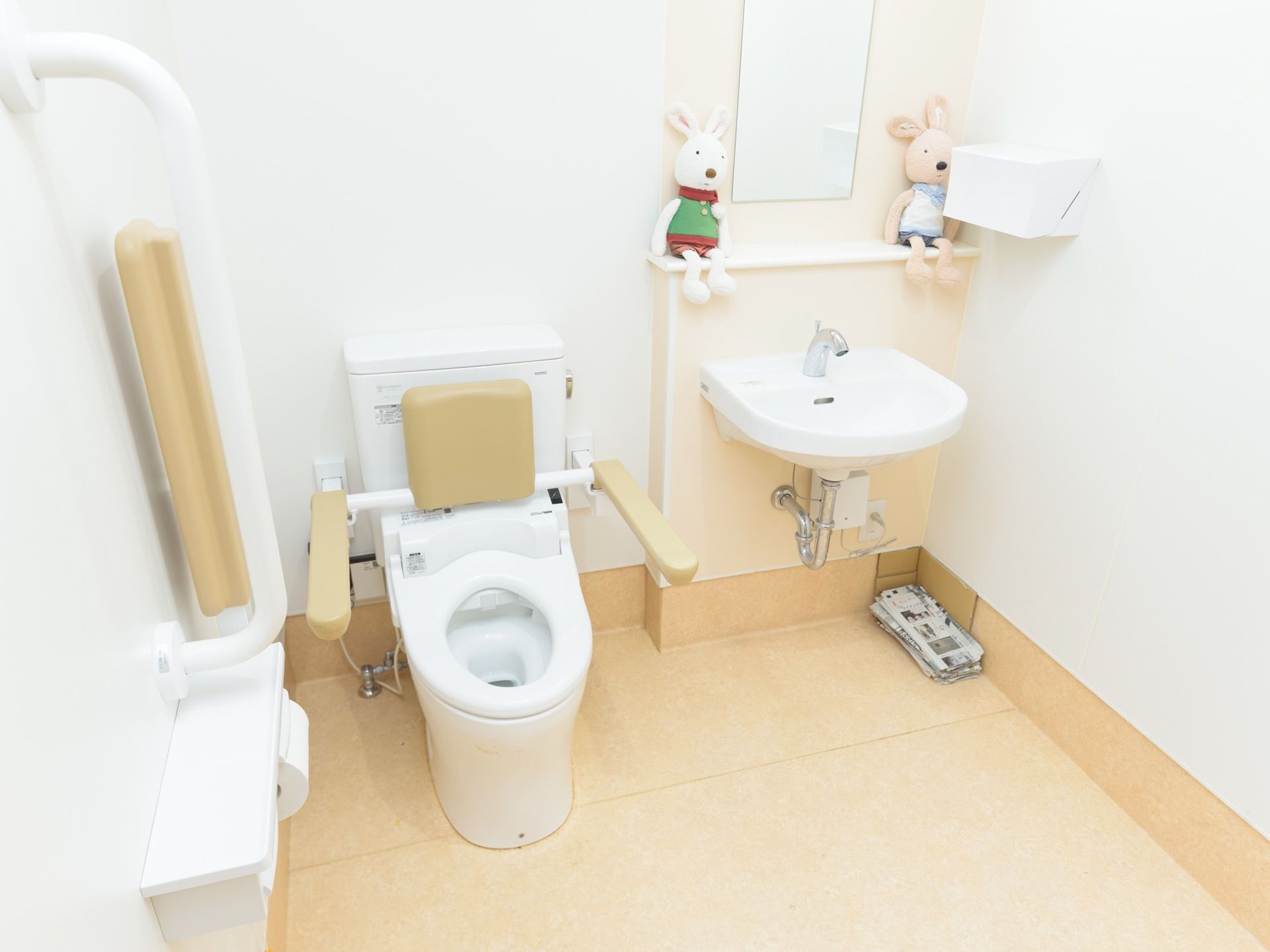 トイレは清潔感のある白い内装で、明るく広々としている。洗面台が併設され、棚には色違いで2体のぬいぐるみが飾られている。
