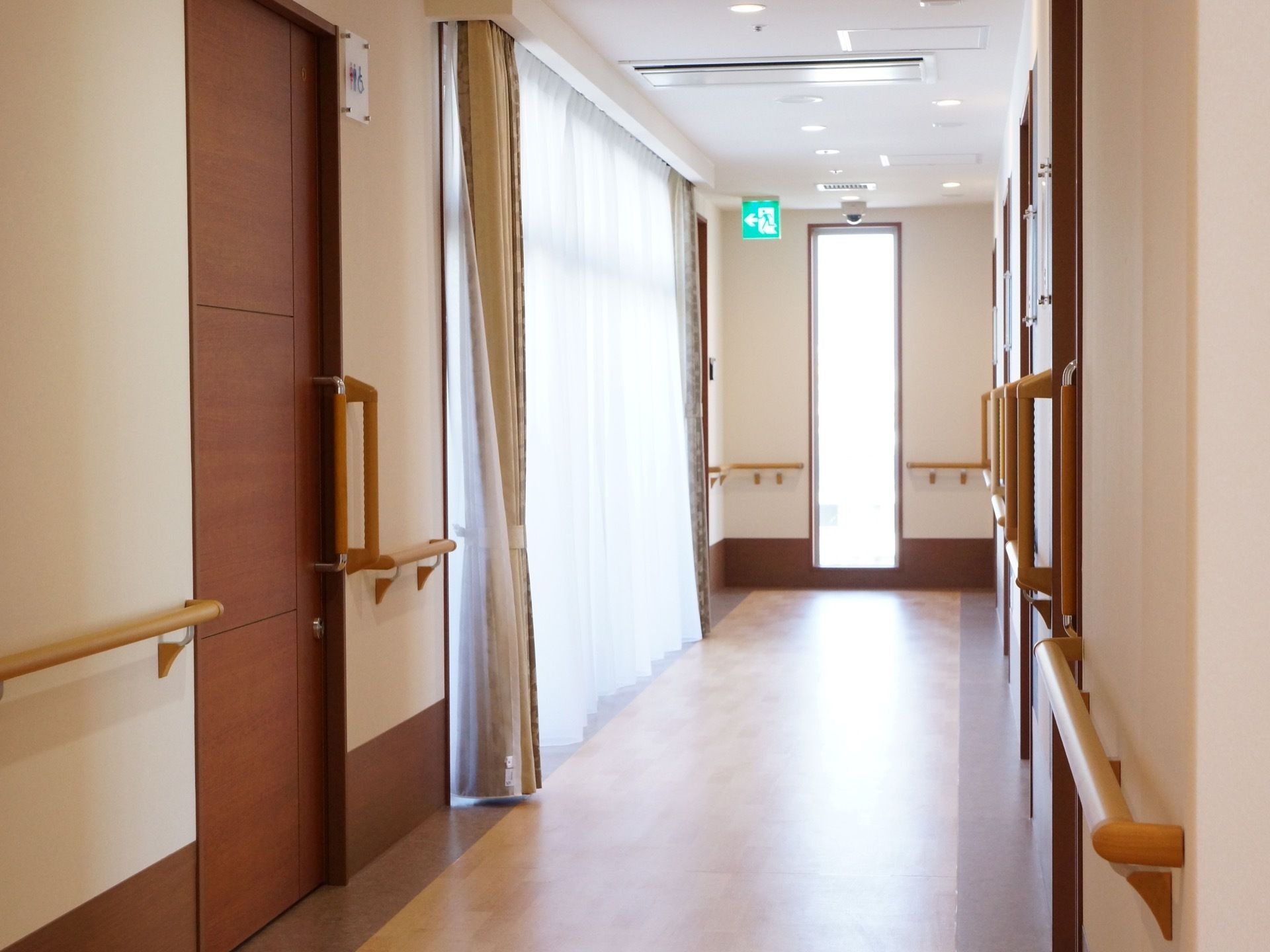 通路には各居室への扉やトイレの扉があり、大きな窓にはカーテンが取り付けられている。突き当たりには非常口への出入口がある。