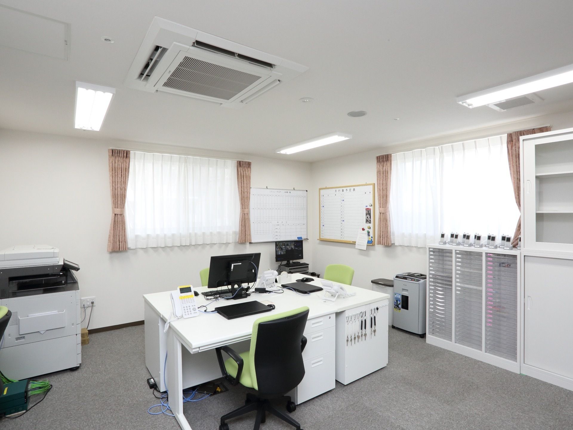 施設を管理している事務所には、部屋の中央に白い机があり上にパソコンが置いてある。壁際には棚やシュレッダー、コピー機などが配備されている。