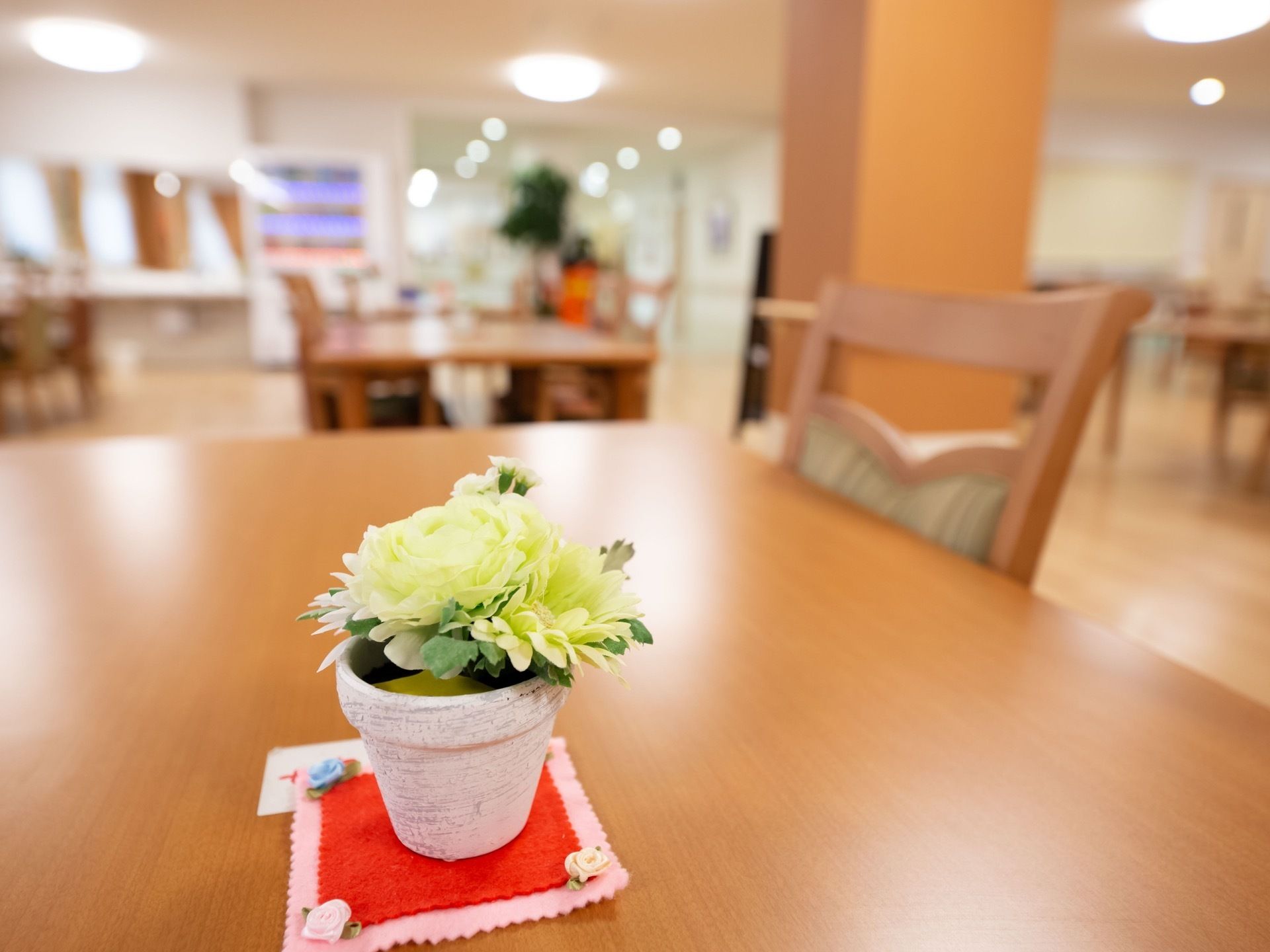 食堂には木製のテーブルと椅子がある。椅子は背もたれが高いものである。テーブルの上には小ぶりな花が飾られている。