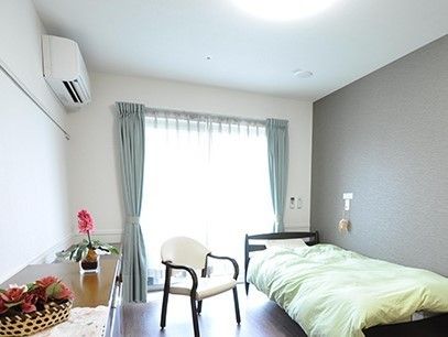 ひとりで部屋でくつろいでいる男性。ホワイトを基調とした部屋で明るい様子が分かる