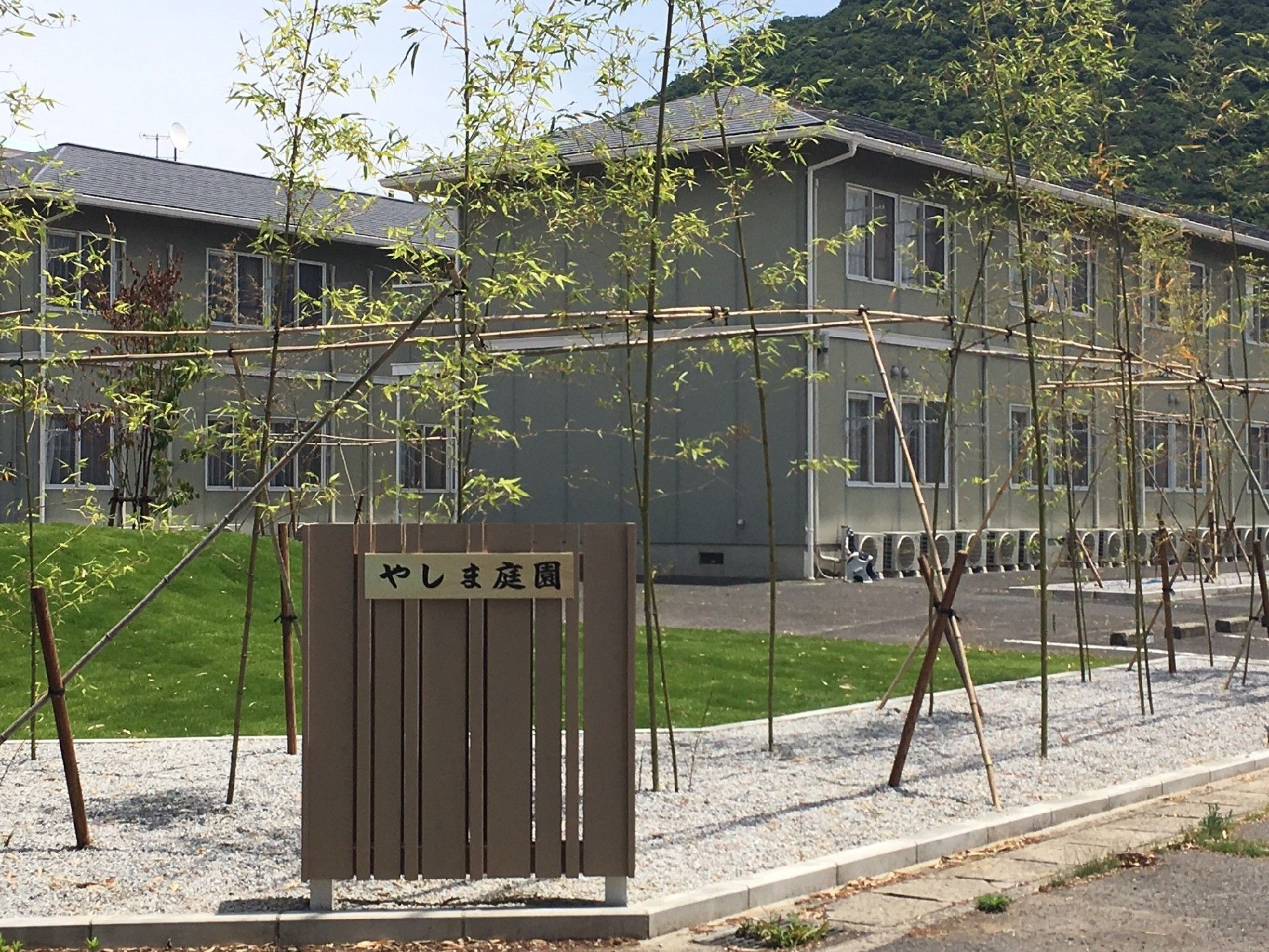 自然に囲まれた、深緑色の２階建ての施設。各部屋には大きな窓があり、空調を完備している。建物周辺には駐車スペースがある。