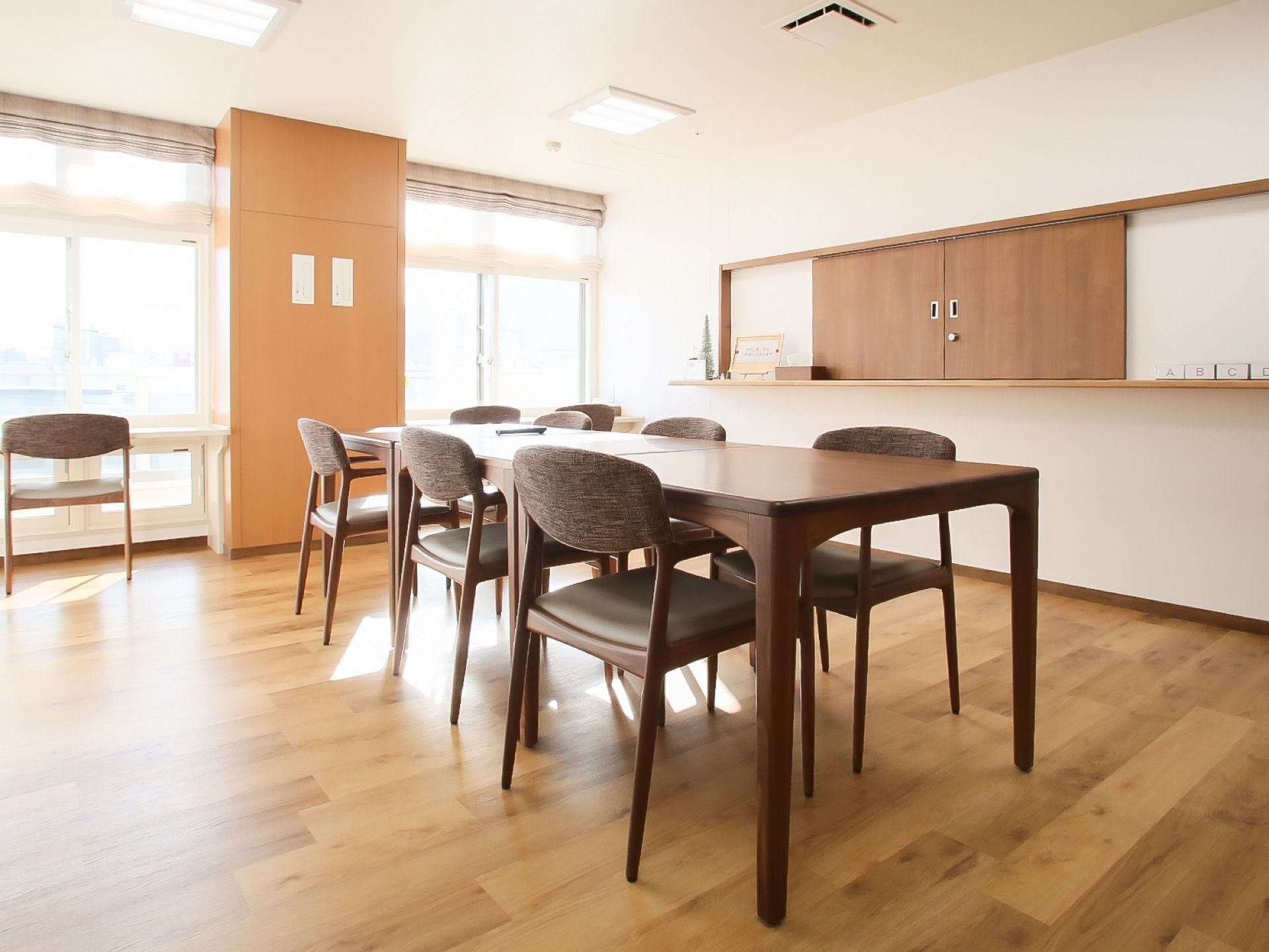 部屋の一方はすべて窓になっていて、室内に日の光が入る明るい空間。長いテーブルが置かれたほかに窓辺には作りつけのテーブルが設置されている。