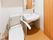 トイレには温水洗浄便座が置かれ、便座周りには手すりが設けられている。壁の色は白色系で、鏡と洗面台が設置されている。