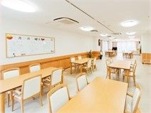広いスペースの床には木製のテーブル、手すり付きの椅子が置かれている。安全に利用できるように壁には手すりを取り付けている。